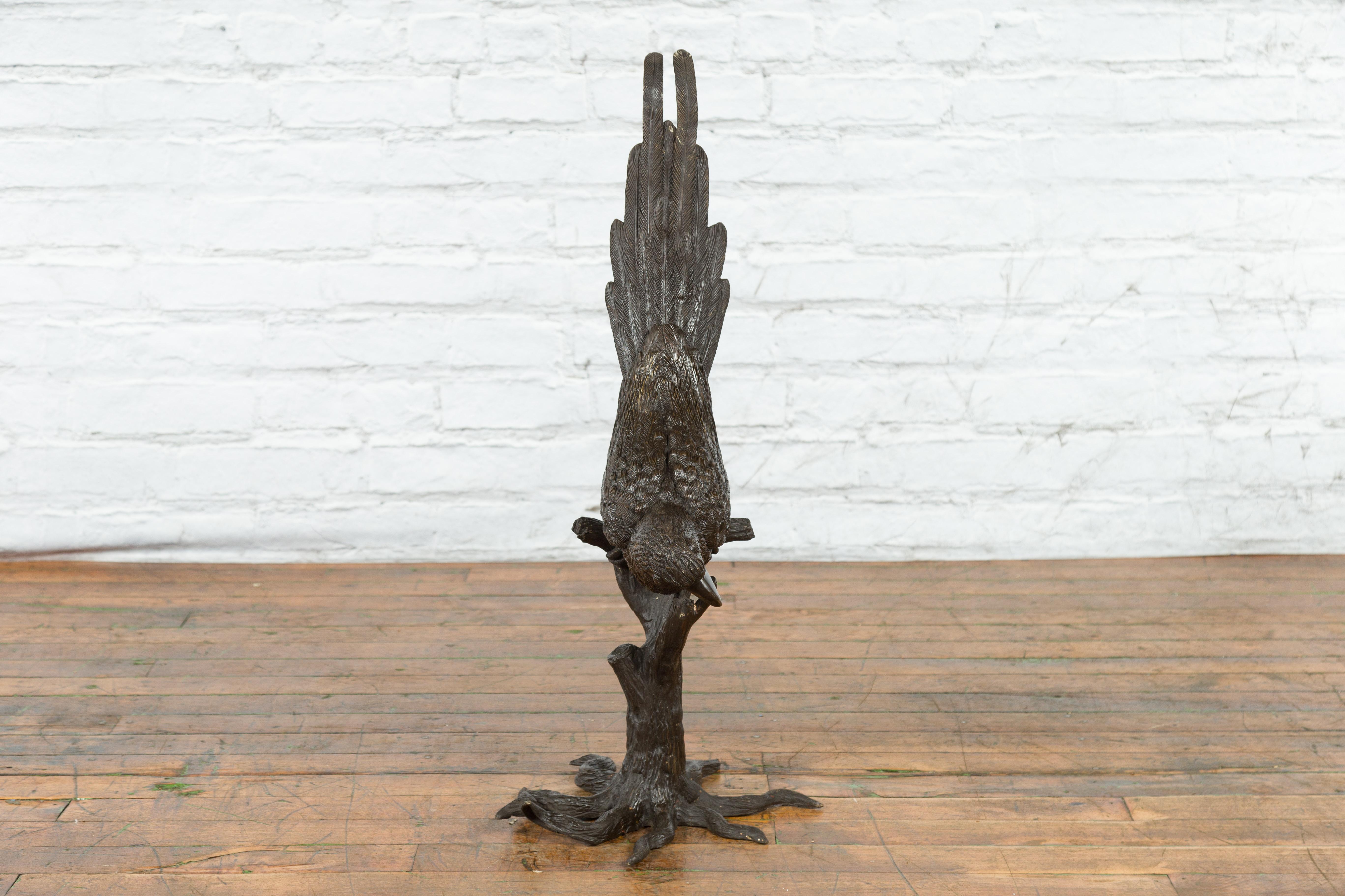 Statue en bronze coulée à la cire perdue d'un perroquet appuyé sur une branche d'arbre à la patine sombre. Créée selon la technique traditionnelle de la cire perdue (à la cire perdue) qui permet une grande précision et finesse dans les détails,