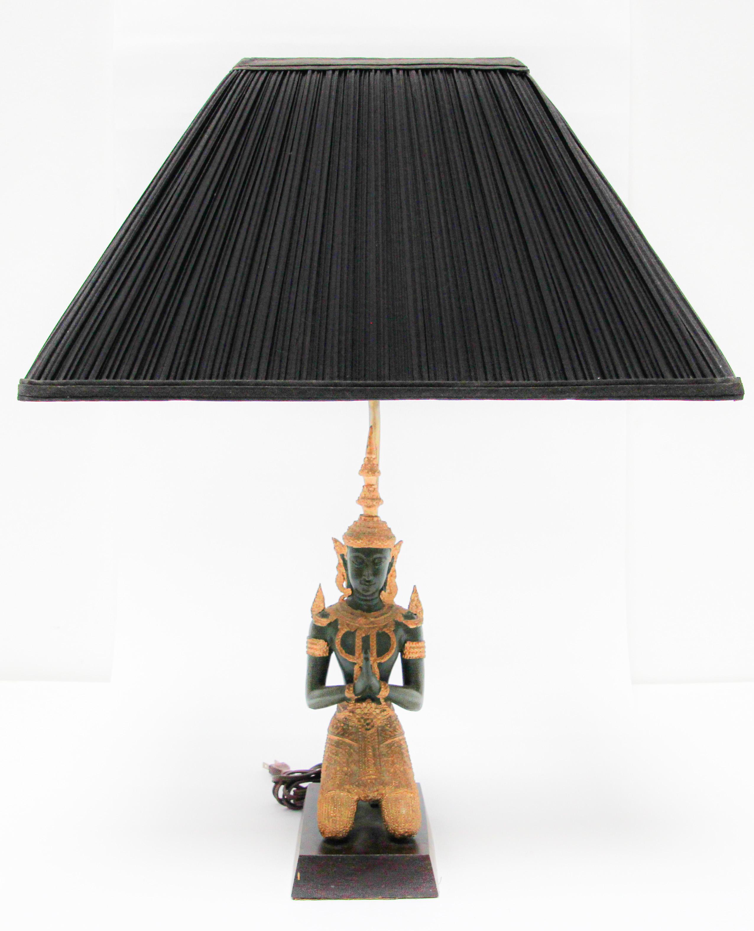 Bronze statue of a Thai Teppanom kneeling Angel Buddha made into a table lamp.
Intricate bronze Thai Teppanom Kneeling Angel Buddha sculpture dark green with gold leaf detailing. 
Thai gilt hand cast Buddha figure lamp, circa 1940.
This bronze