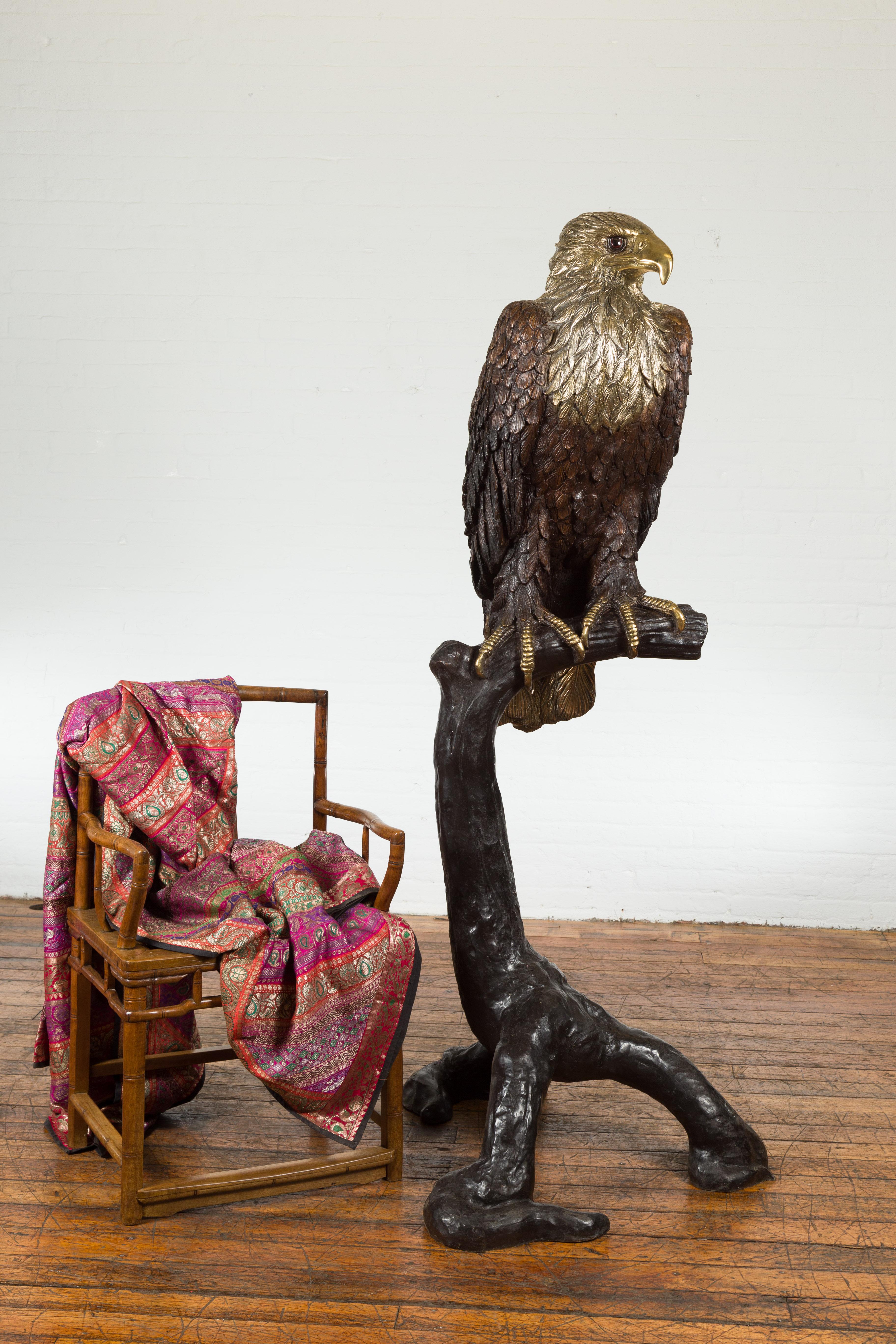 A lost wax cast bronze life size statue of an eagle on a tree branch with gold and silver highlights and two toned eyes. This is a current production and this one is available now. This lost wax cast bronze life size eagle statue is a captivating