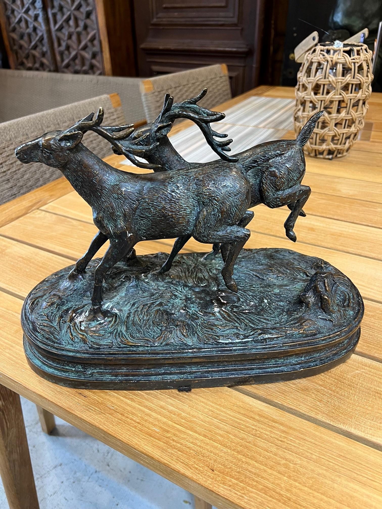 A bronze statue of two deer running with their hind legs kicking up. This is a nice table top bronze of two stags running that would look great on a desk or coffee table. It does not have a signature but is a good quality bronze in good condition.