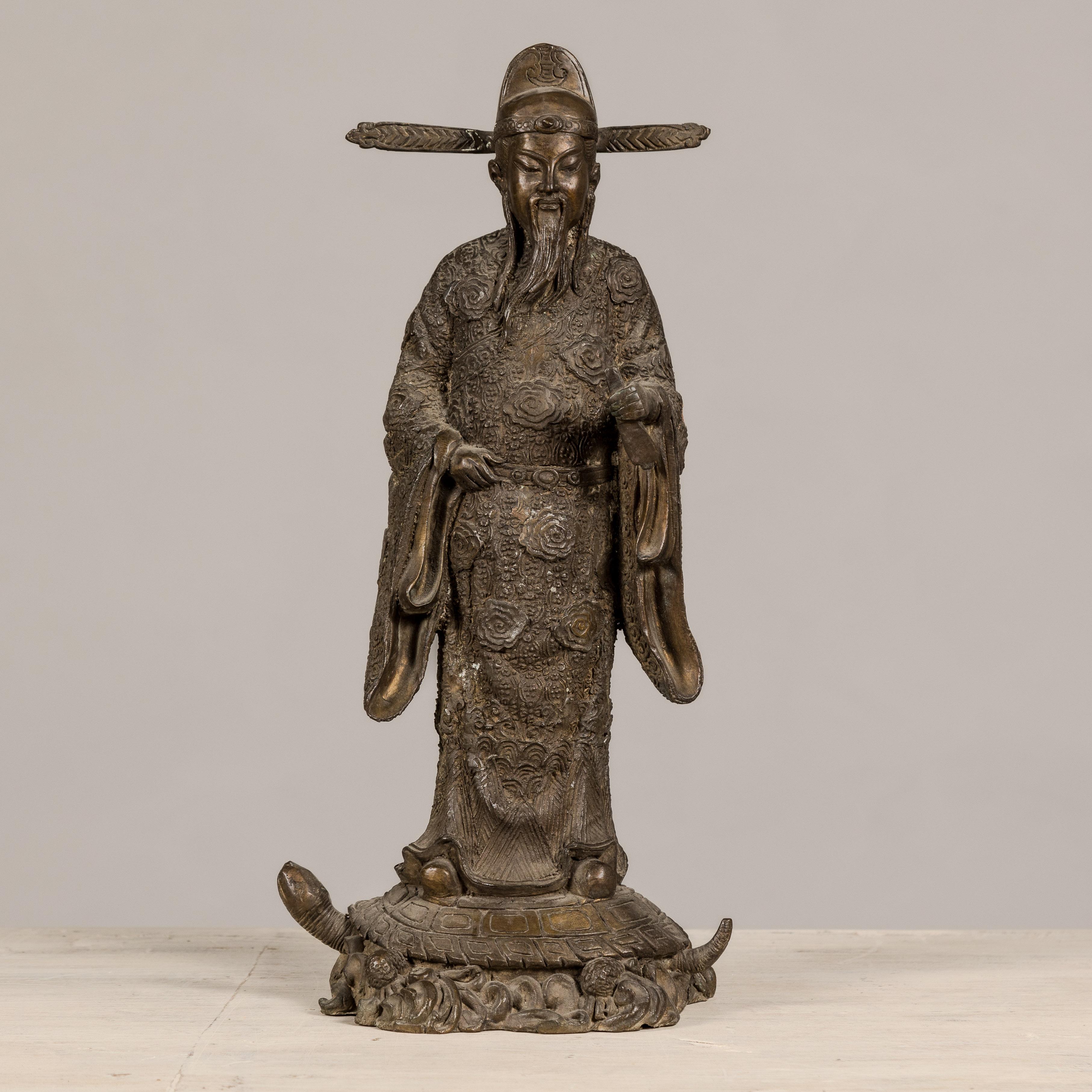 A Chinese vintage bronze statuette depicting a scholar standing on a turtle. This Chinese bronze statuette, exquisitely crafted to depict an old scholar, is a piece that combines traditional symbolism with detailed artistry. 

The statue portrays an
