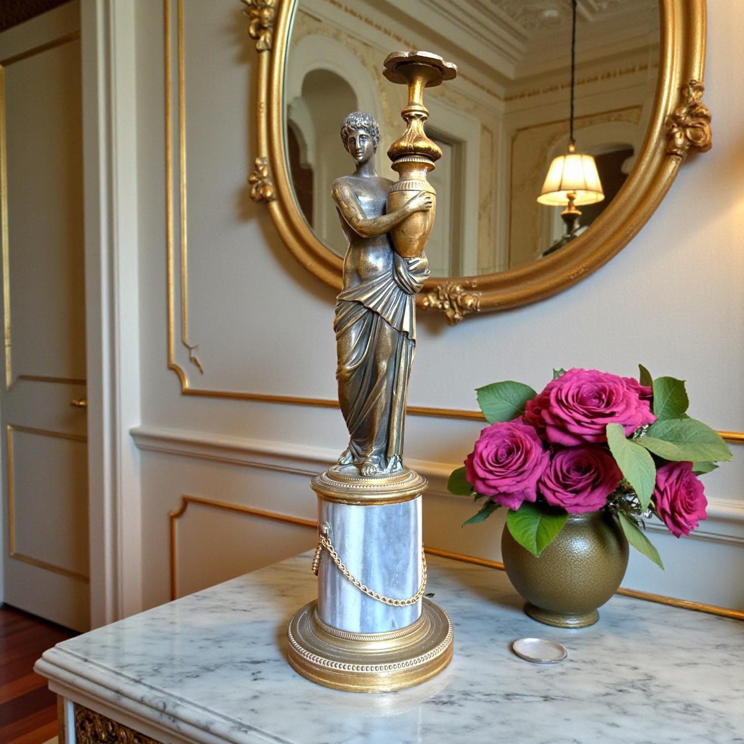 Elegant decorative statuette from the French Restoration period, depicting a Classical young man finely sculpted in bronze and draped in generously pleated garments that partially reveal his body. The youthful face and short hair, rendered with