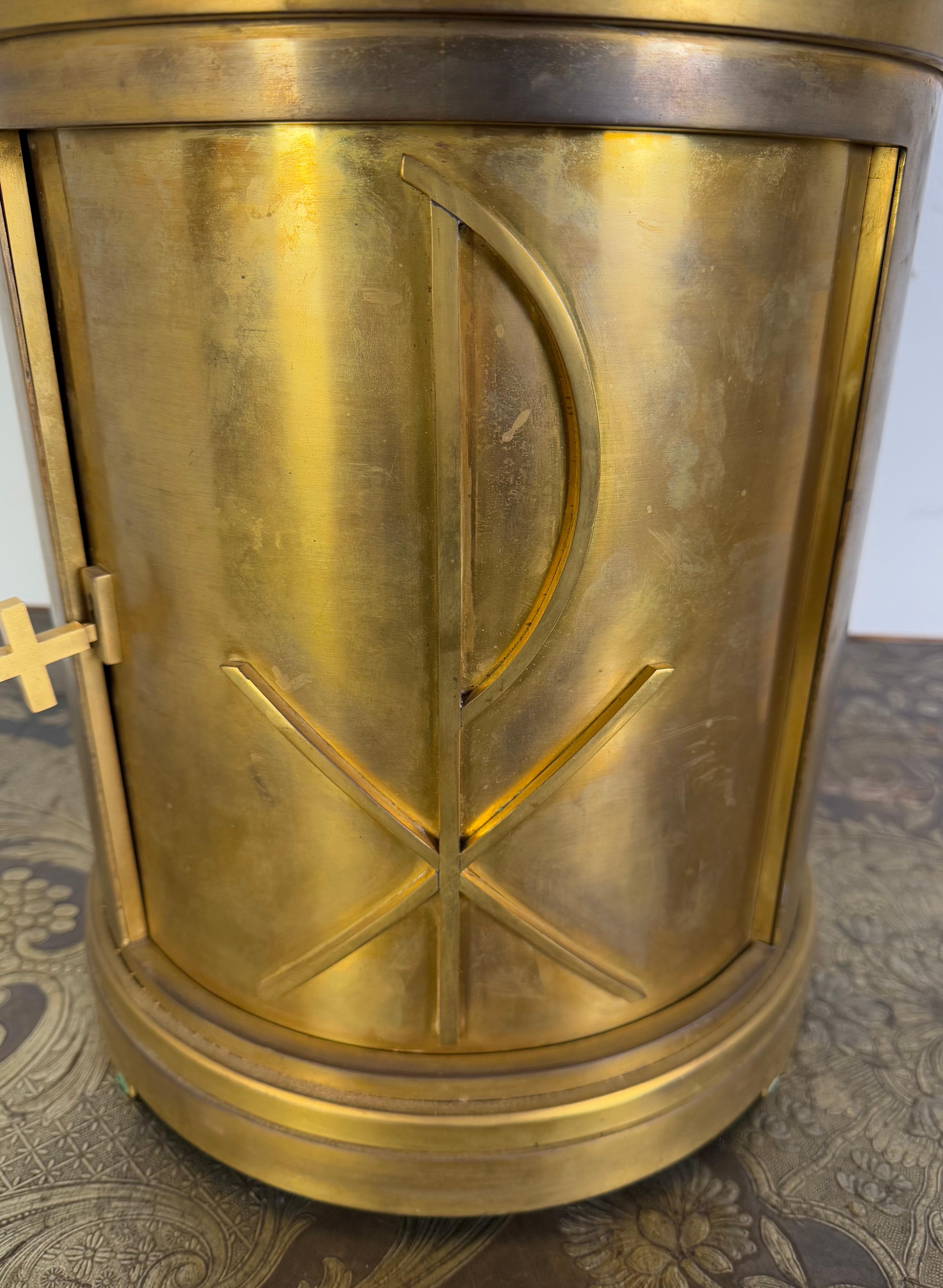 Il s'agit d'un tabernacle en bronze fabriqué et estampillé par les Ateliers d'Art Liturgique Cheret, un atelier réputé pour la qualité de son art ecclésiastique et liturgique.  Le tabernacle a une forme cylindrique avec un sommet conique, couronné