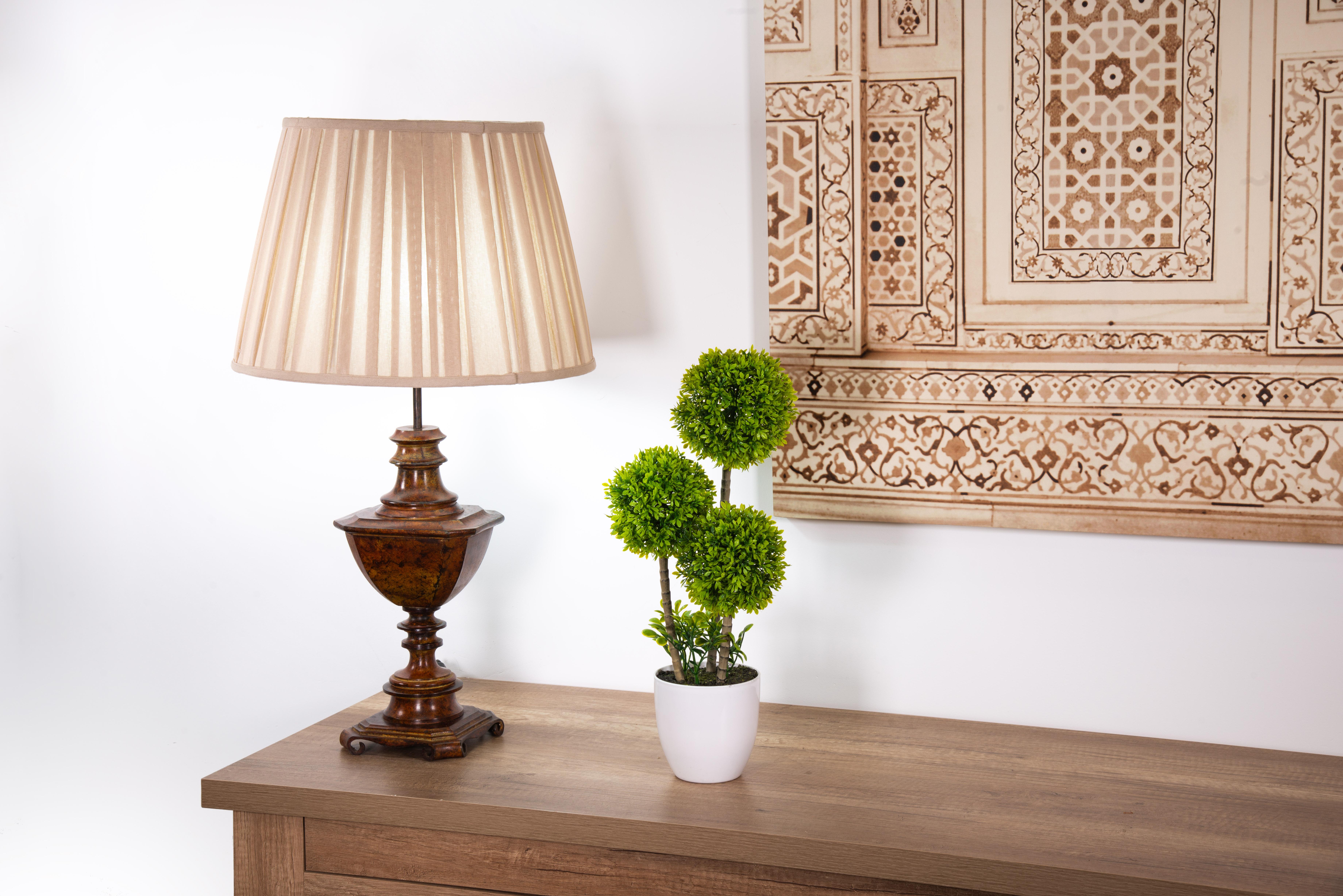 Bronze table lamp in the shape of a rectangular cup. No screen.
 A base on four legs formed by volutes turned inwards ensure the stability of the lamp, whose foot is shaped like a rectangular cup: a round base gives way to several concave sections