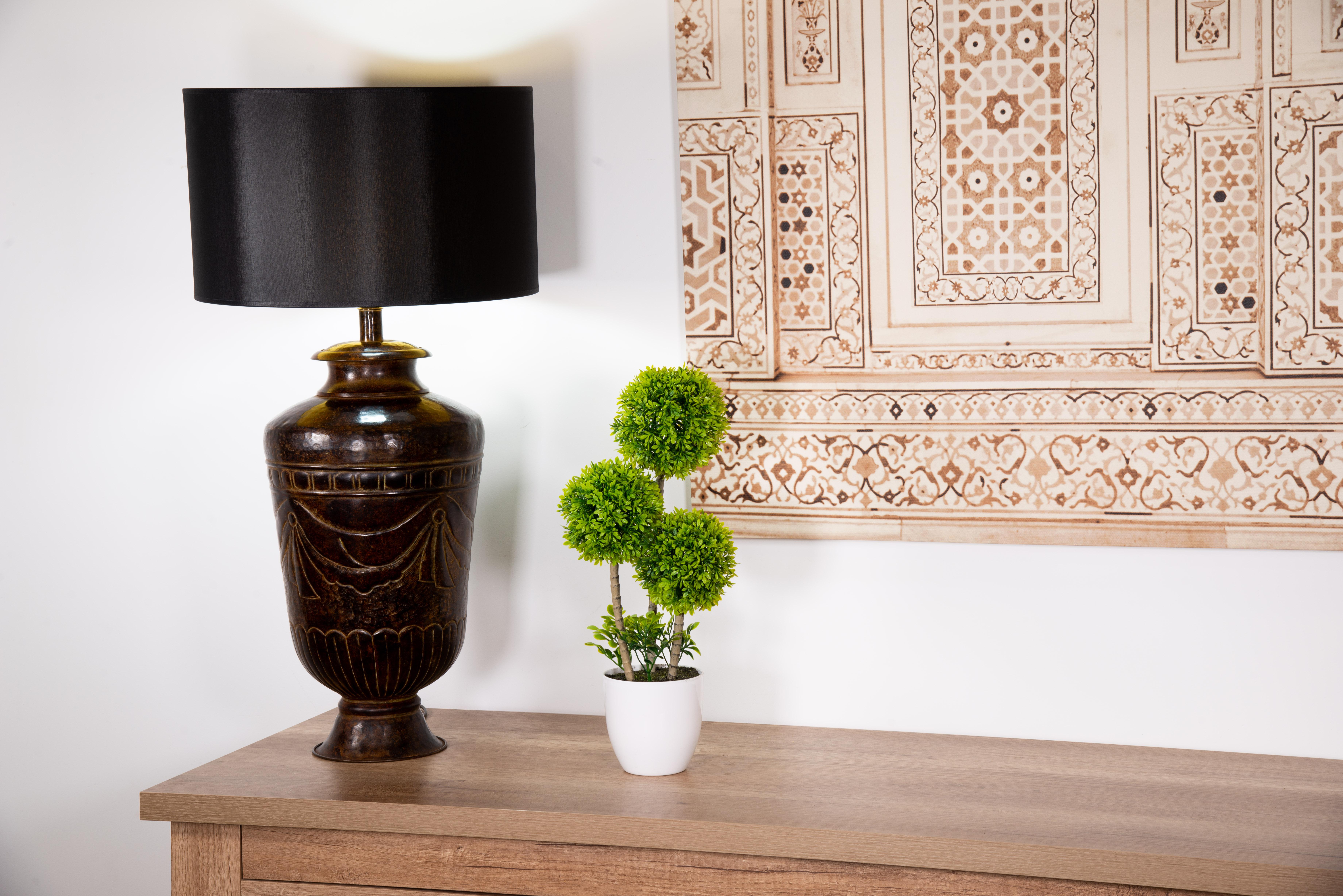 Vase-shaped table lamp in patinated metal. 
No screen. 
A circular foot serves as the base of the work, shaped like a stylized truncated conical vase or jar and decorated with a garland flanked by waves below and squares between fine moldings above.