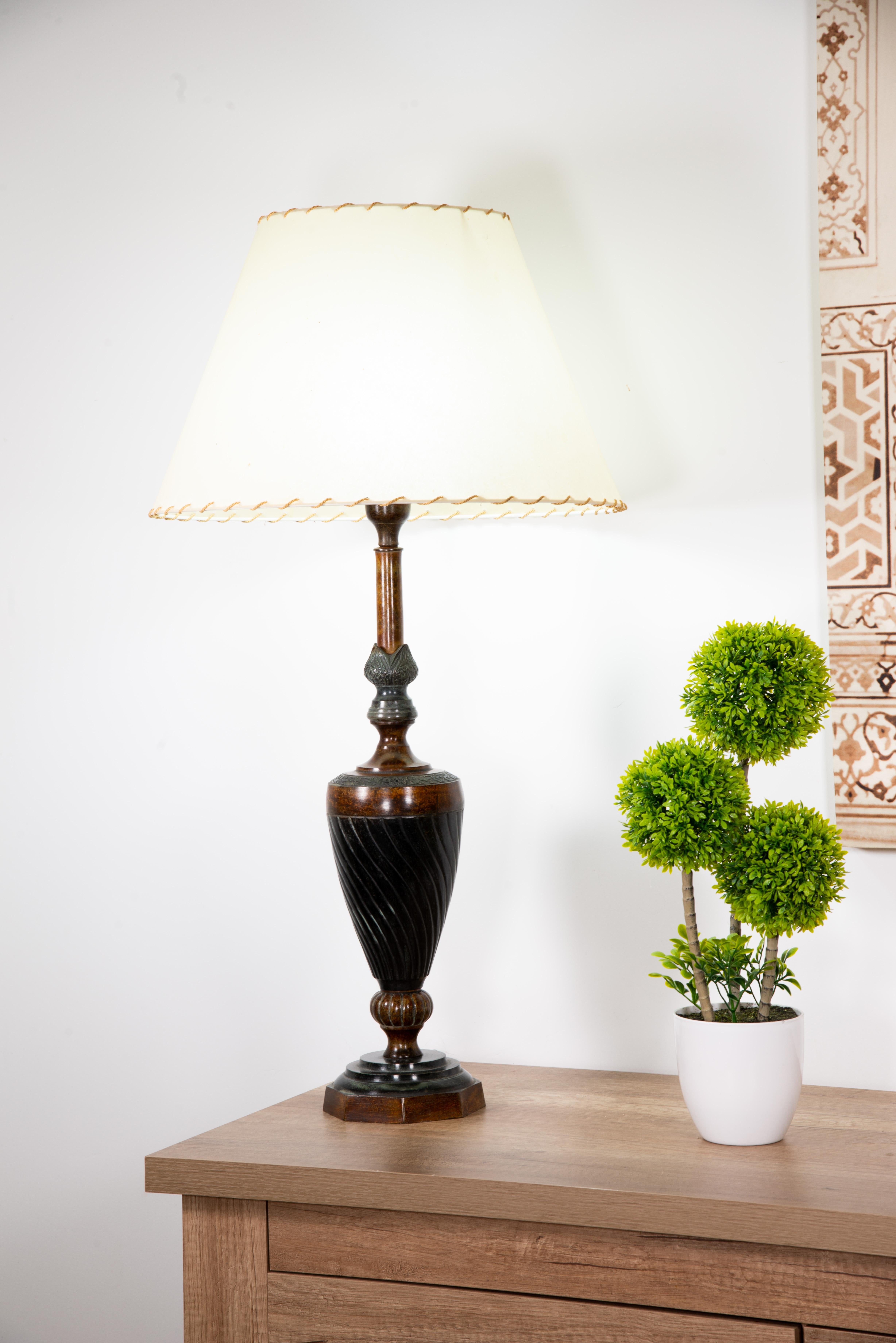 Lampada da tavolo in bronzo patinato. Lo schermo non è incluso. 
Lampada da tavolo a forma di vaso con base circolare e corpo decorato con morbide spirali di influenza classicista. La parte superiore presenta dei raffinati rilievi vegetali e una