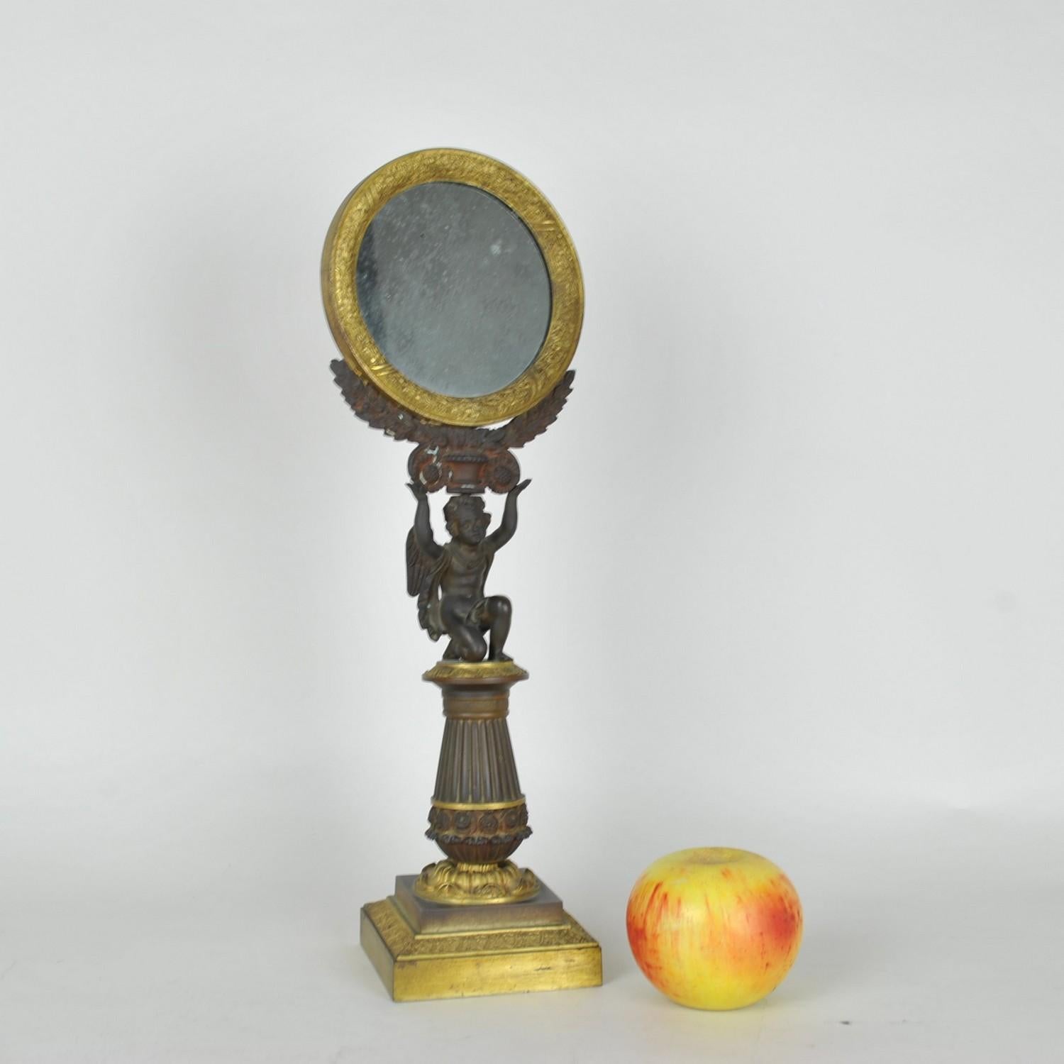 Miroir de table en bronze à double patine, avec un ange ailé agenouillé soutenant le miroir rond avec une couronne de laurier

Période de restauration, Usure de la patine

Mesures : hauteur 39 cm
diamètre du miroir 13cm
9.5 x 9.5 cm.