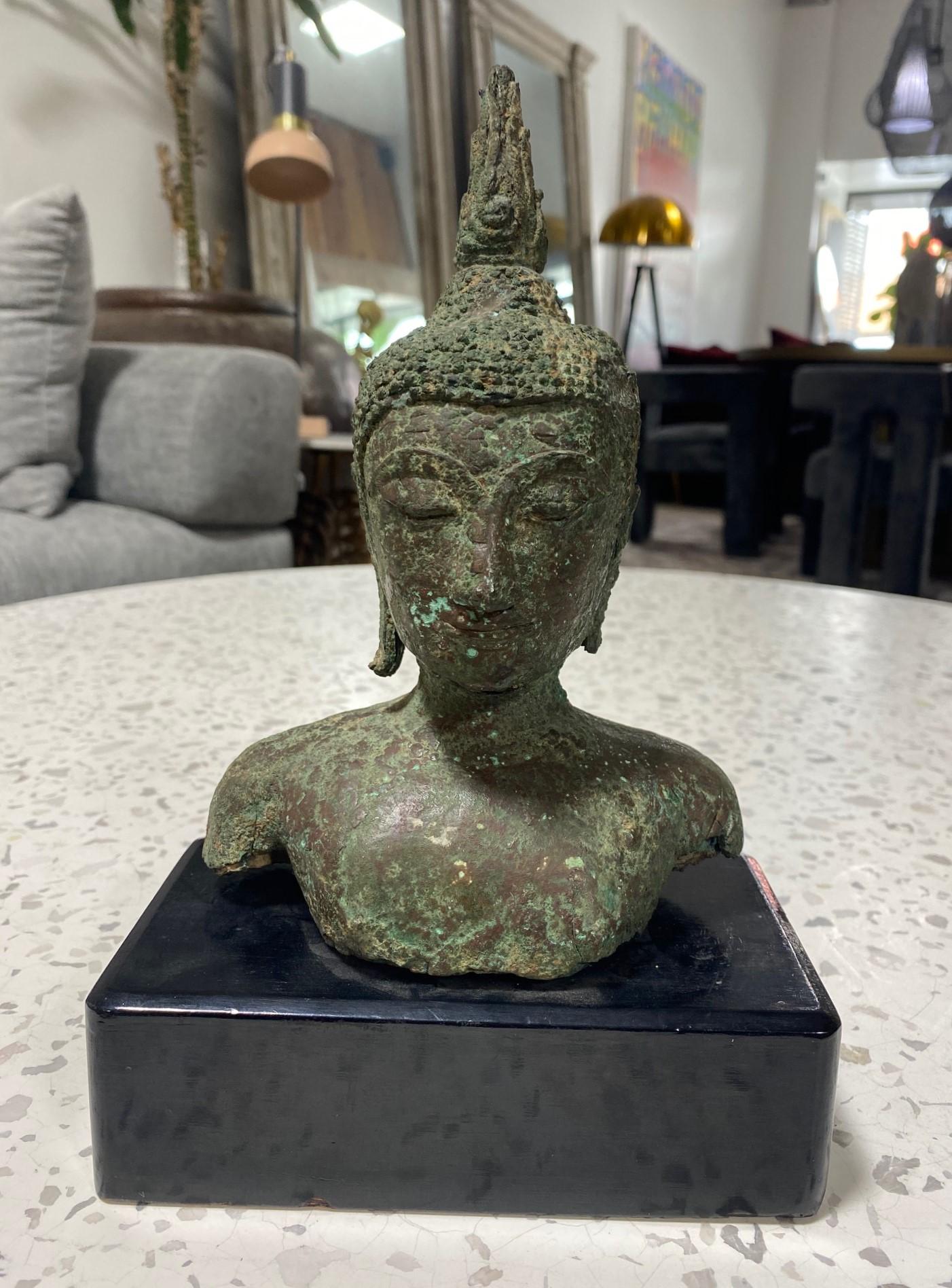 A beautifully sculpted Thai/ Siam Southeast Asian bronze Buddha head on a custom wood stand. The Buddha's eyes are closed in serene meditation. The piece has a wonderful feel and heft to it. Very well well crafted with a gorgeous natural organic