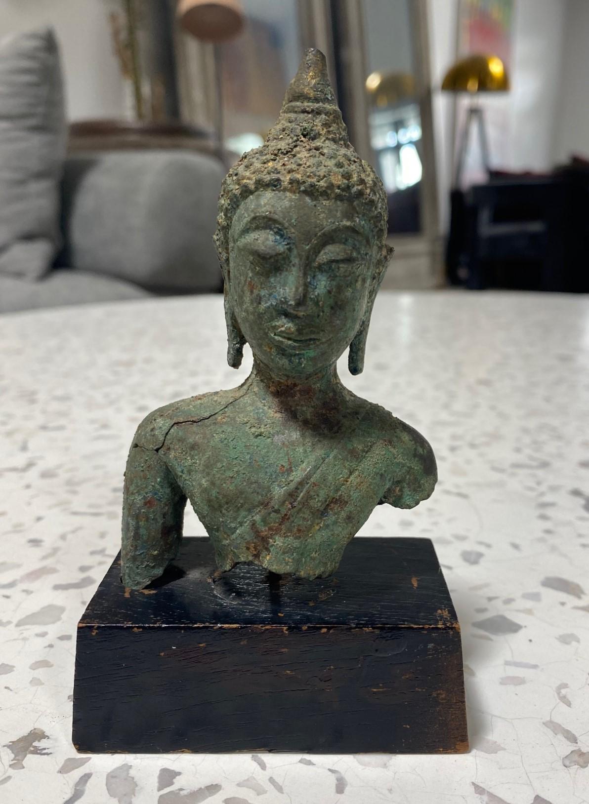 A beautifully sculpted Thai/ Siam Southeast Asian bronze Buddha head on a custom wood stand. The Buddha's eyes are closed in serene meditation. This beautiful gem has a wonderful feel and heft to it. Very well well crafted with a gorgeous natural