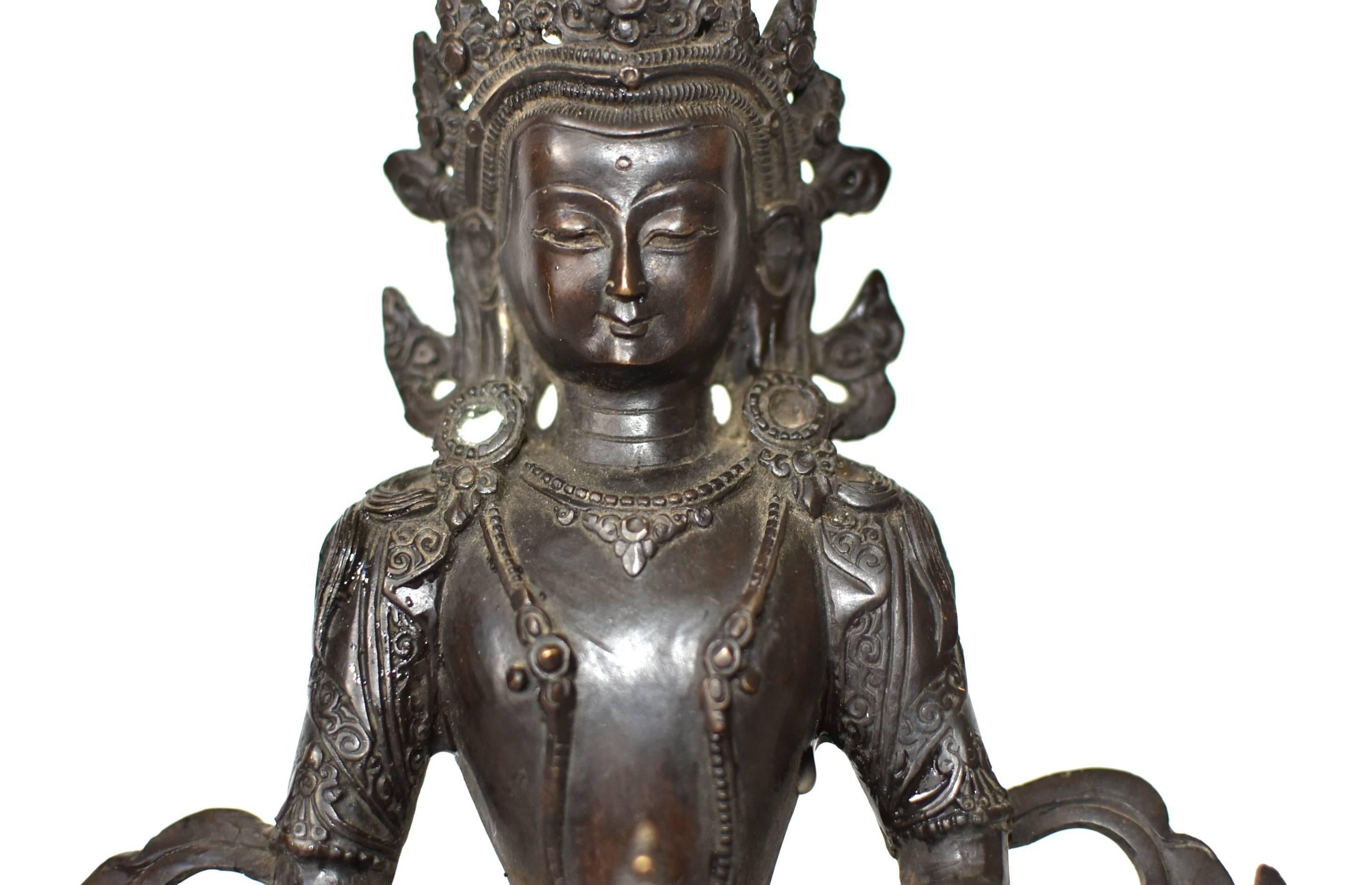 A beautiful bronze sculpture of The Tibetan Amitayus, the Bodhissatva/Buddha of infinite life, a tantric for of Amitabha, the Buddha of Infinite Light. 
Adorned with necklaces, crown and sashes decorated with rosettes, pearls and medallions, Buddha