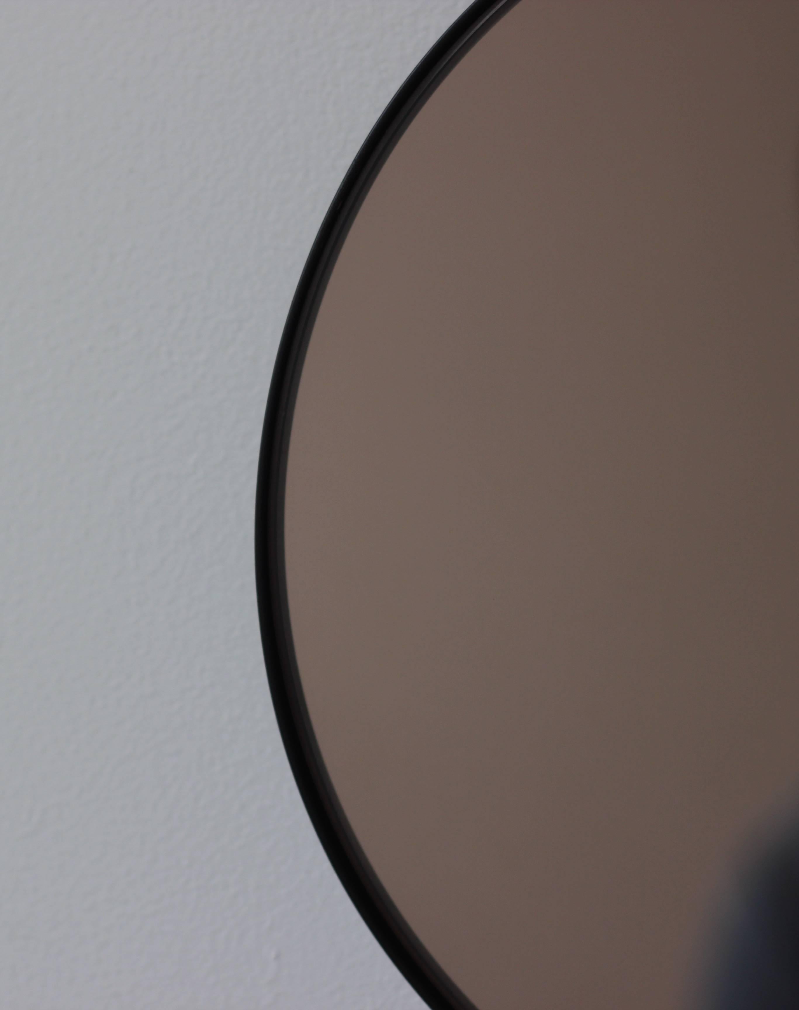 Contemporary Orbis™ round bronze tinted mirror with a minimalist aluminium powder coated black frame. Designed and handcrafted in London, UK.

Medium, large and extra-large mirrors (60, 80 and 100cm) are fitted with an ingenious French cleat (split