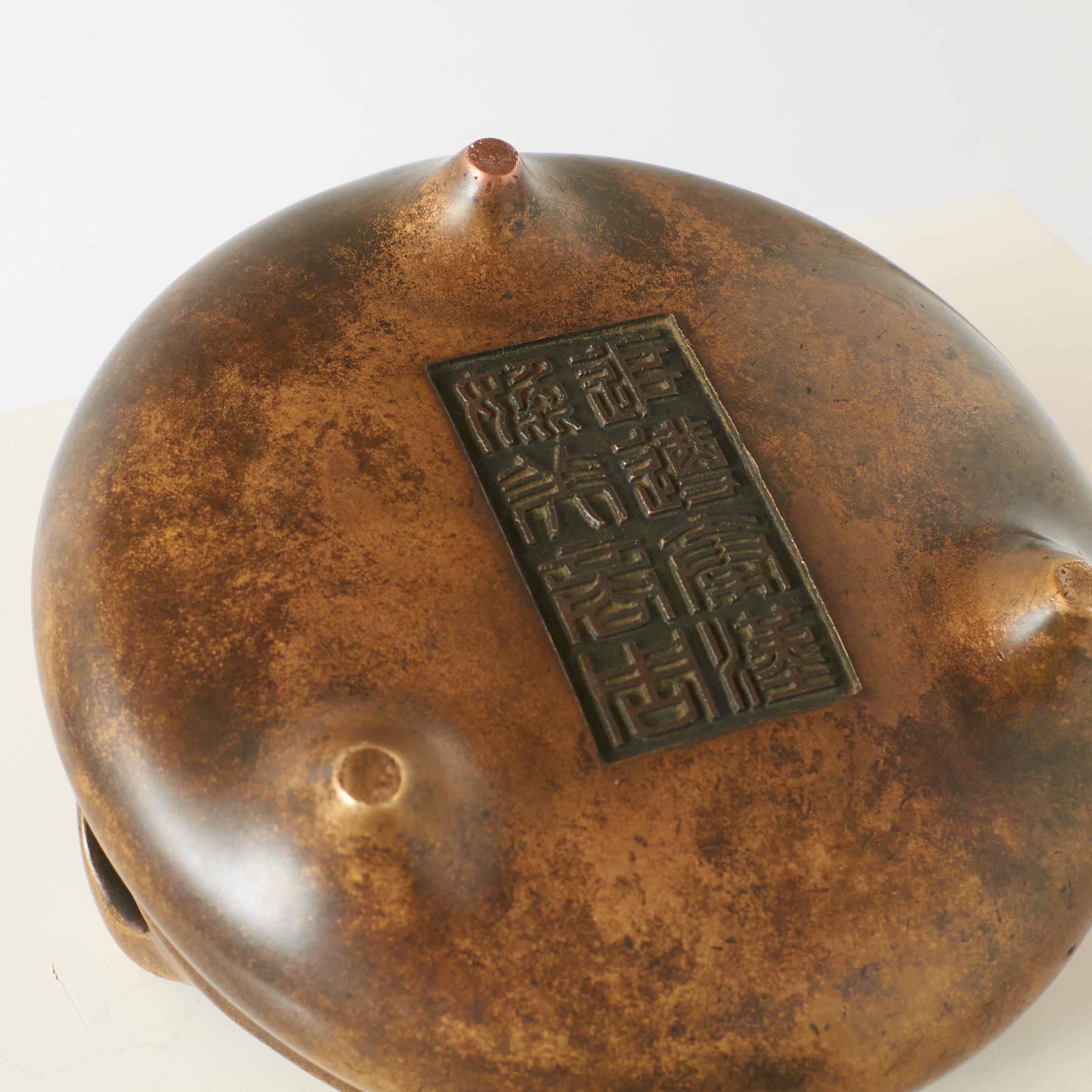 Bronze Tripod Censer with Double Ears

Chinese bronze censer with a rounded, squat body supported by three short legs and flanked by upright double handles. The surface has a mottled brown patina, reflecting age and use. Traditionally used for