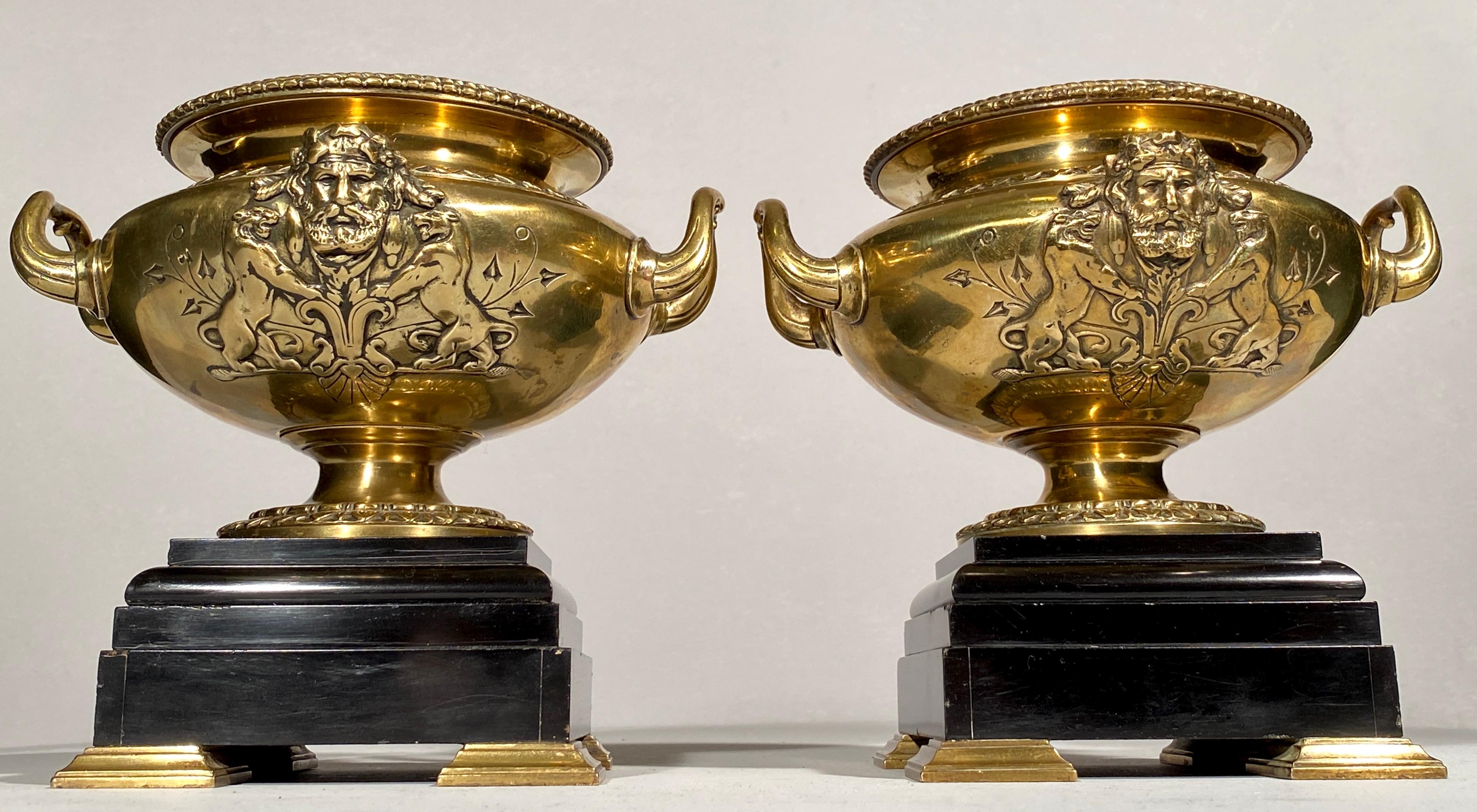 Pair of Bronze Urn Vases French 19th Century on Black Marble Bases. Shaped handles raised on a black marble stepped plinth with a casting of a Greek God on both sides with mirroring lions and engraving details. 


      
     