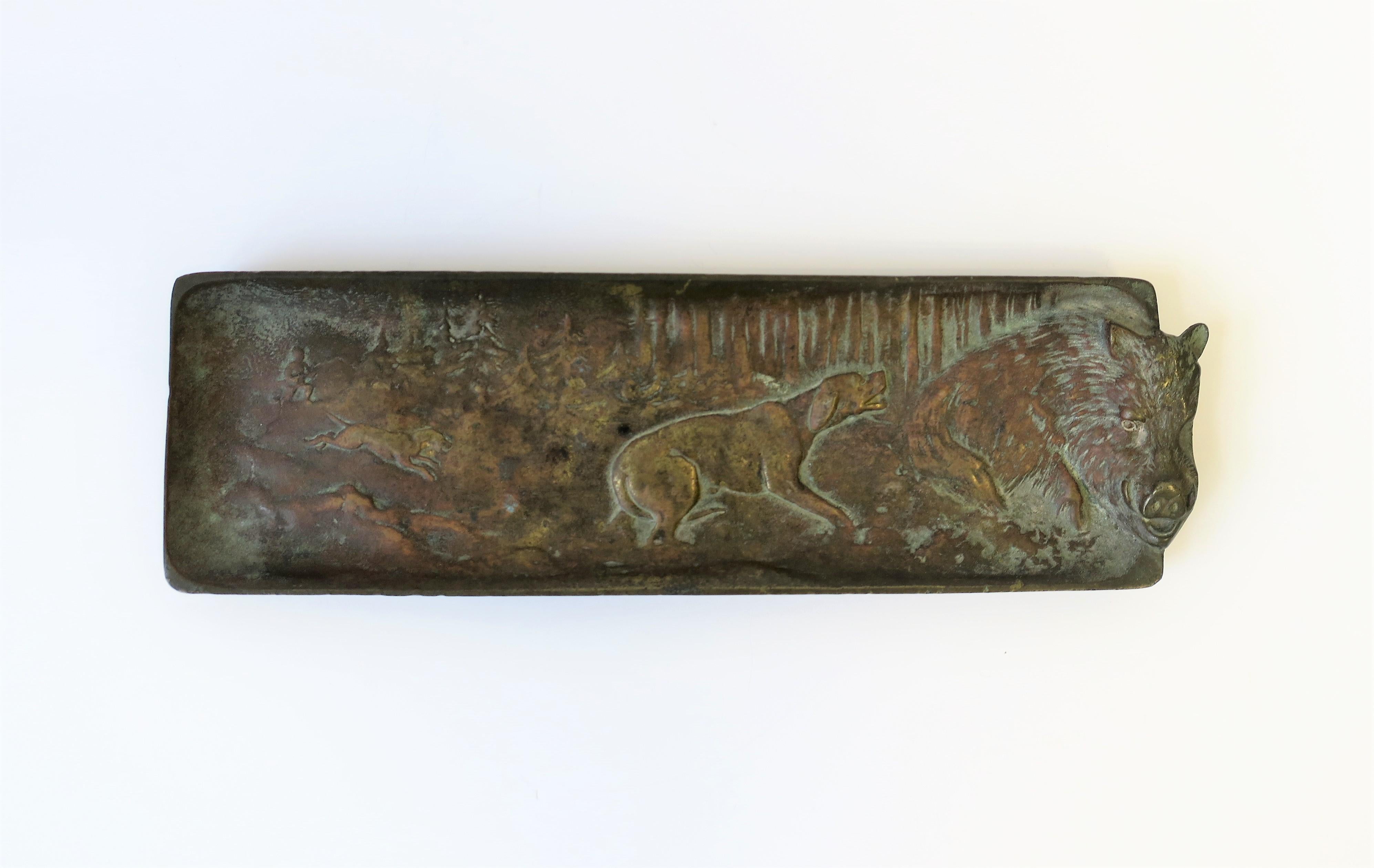 A substantial bronze rectangular tray with raised relief design depicting a 'hunting scene in woods', circa early-20th century. Detailed raised relief scene includes tall pine trees, hunter man, blood hound and retriever dog, and a wild boar. A