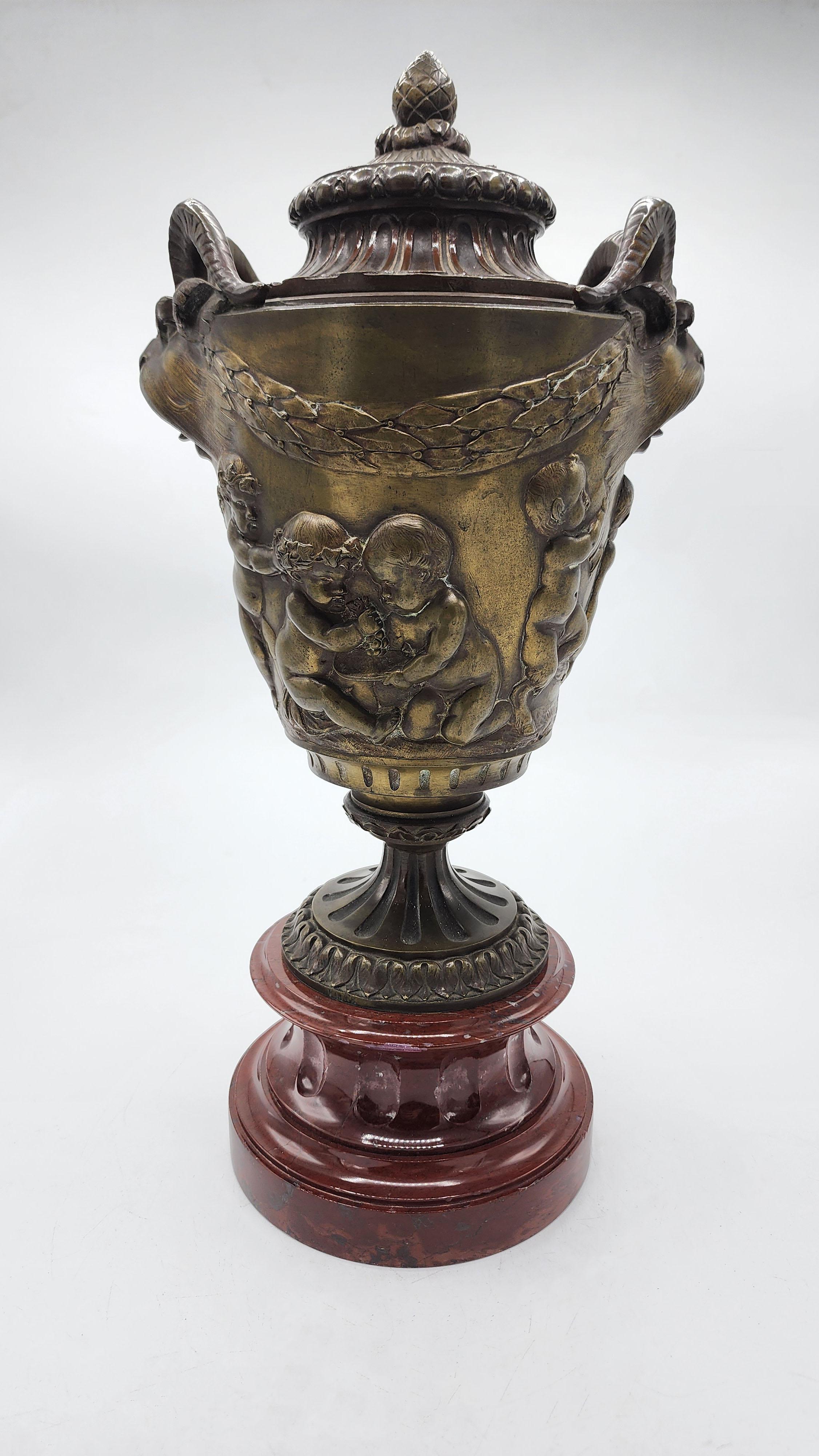 Bronze Vase by Claude Michel Clodion
Bronze with a lid on a red marble base, decorated in relief with scenes of cherubs in various positions and wreaths of flowers, framed by garlands that run around the body of the vase. On the sides, it features
