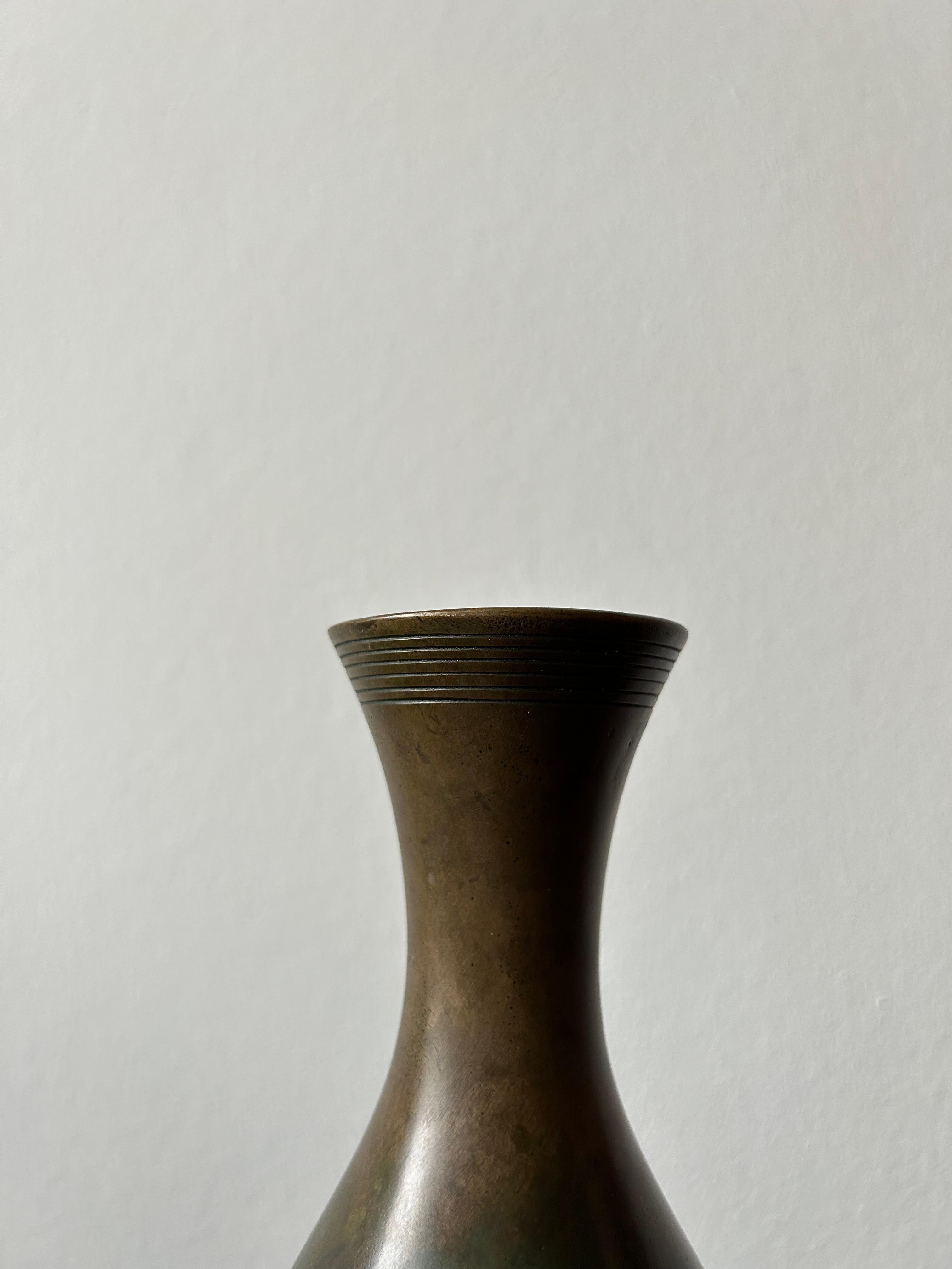 Patinaed bronze vase designed by Just Andersen and manufactured by GAB in Sweden in the 1920s. 

Just Andersen (born 13 July 1884 in Godhavn, Greenland, died 11 December 1943 in Glostrup) was a Danish corpus artist, silversmith and sculptor and,