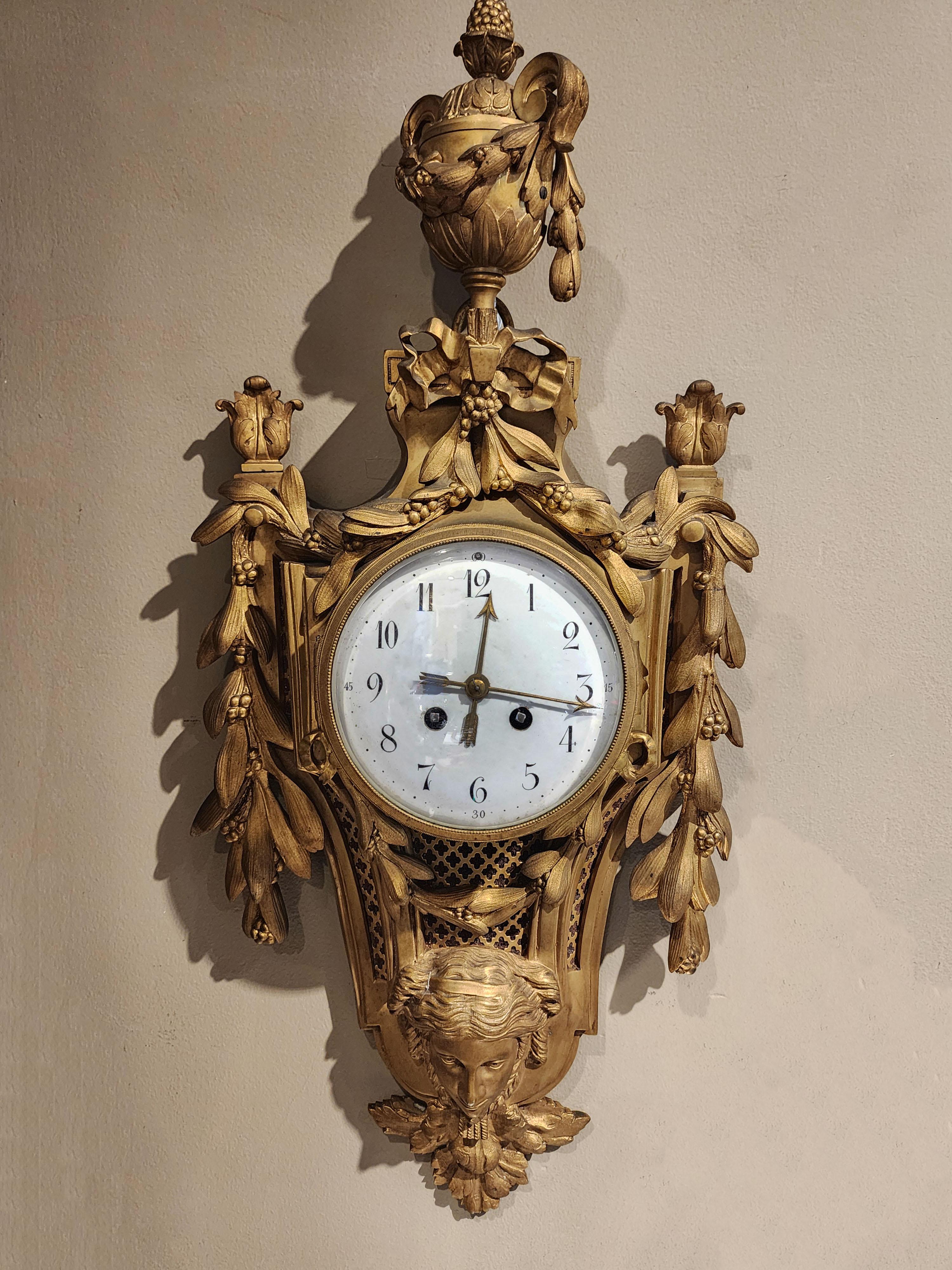 Bronze wall clock, Louis XVI style with a mask
Beautiful bronze clock from the late 19th century decorated with laurel wreaths on the sides, a mask of a woman at the bottom and a terminal with laurels at the top. Although the clock is in a good