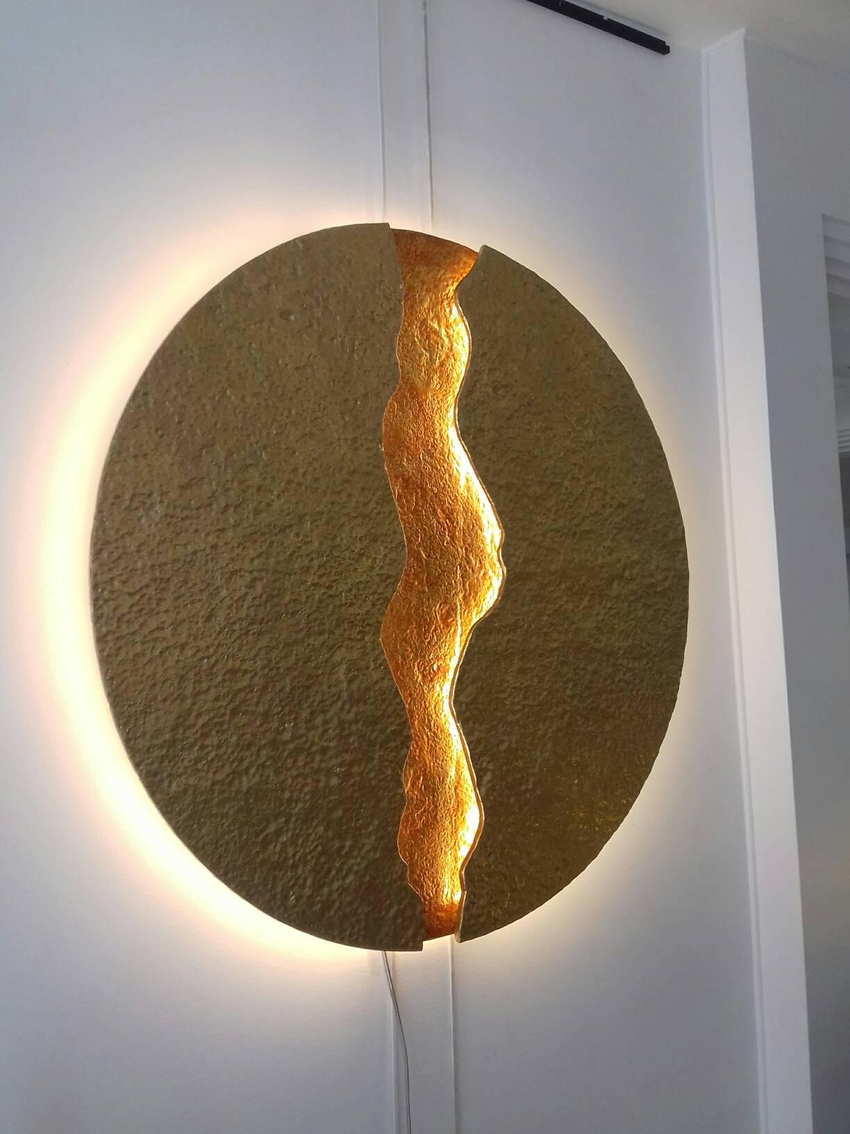 Round wall light, simulating a volcanic lava flow, illuminated on each side of the crack and all around the circle by leds. Double patina gold and orange.