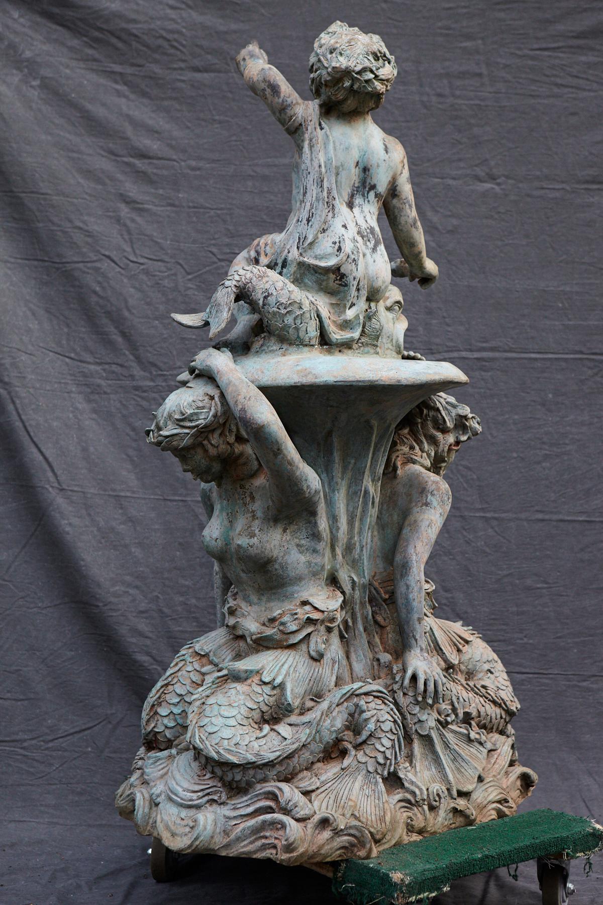 Bronze water garden/fountain statue of a merman and a mermaid carrying a merboy and a dolphin on their shoulders. The statue has a wonderful, lovely green patina. The statue is piped.
Additional photos can be provided on request, as the space is
