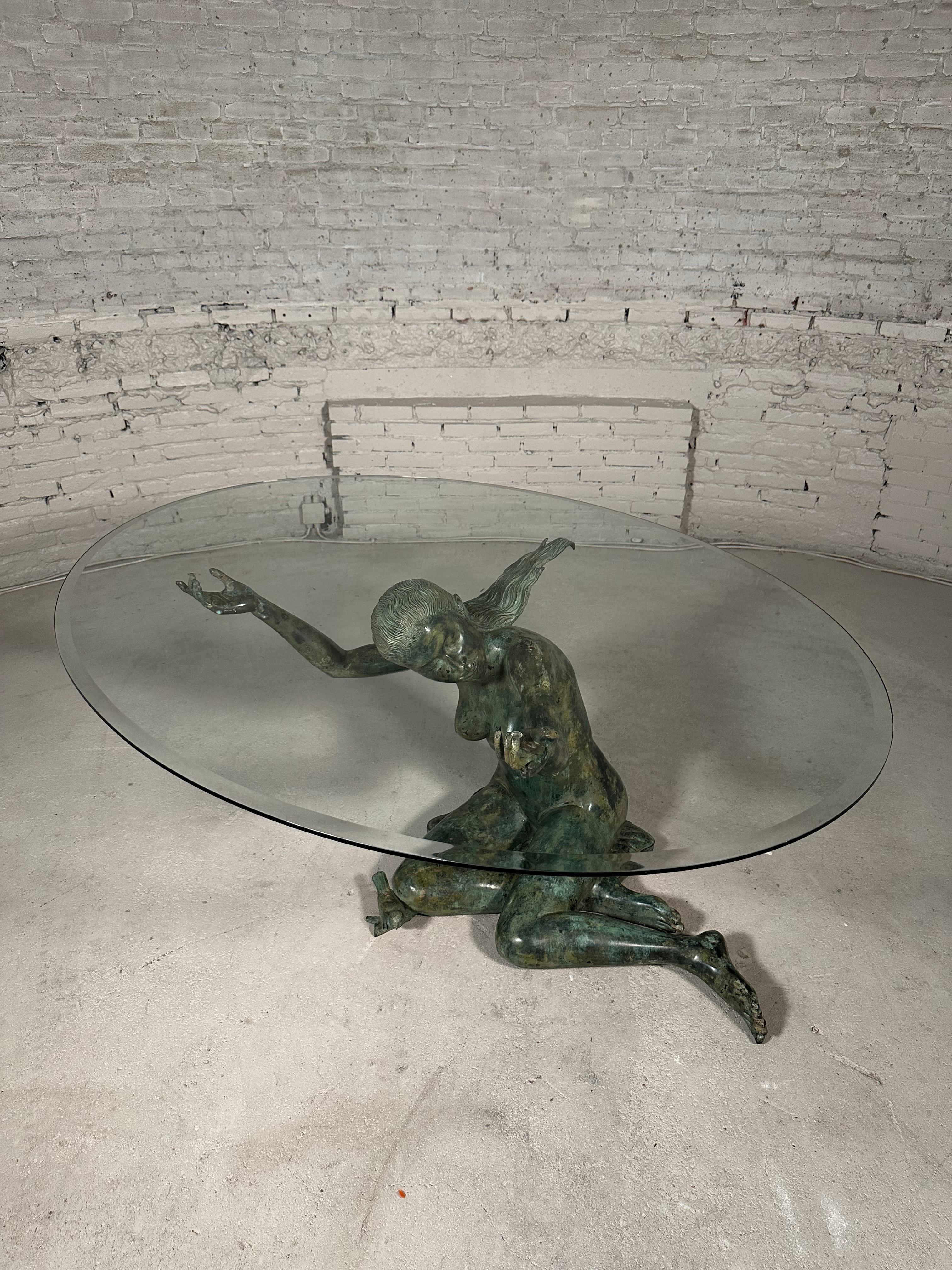 This unique dining table features an exquisite bronze sculpture of a woman, accompanied by a little bird at her knee. With exquisite detailing, the sculpture holds a glass table top. This 1970's piece showcases the beauty of art and functionality in