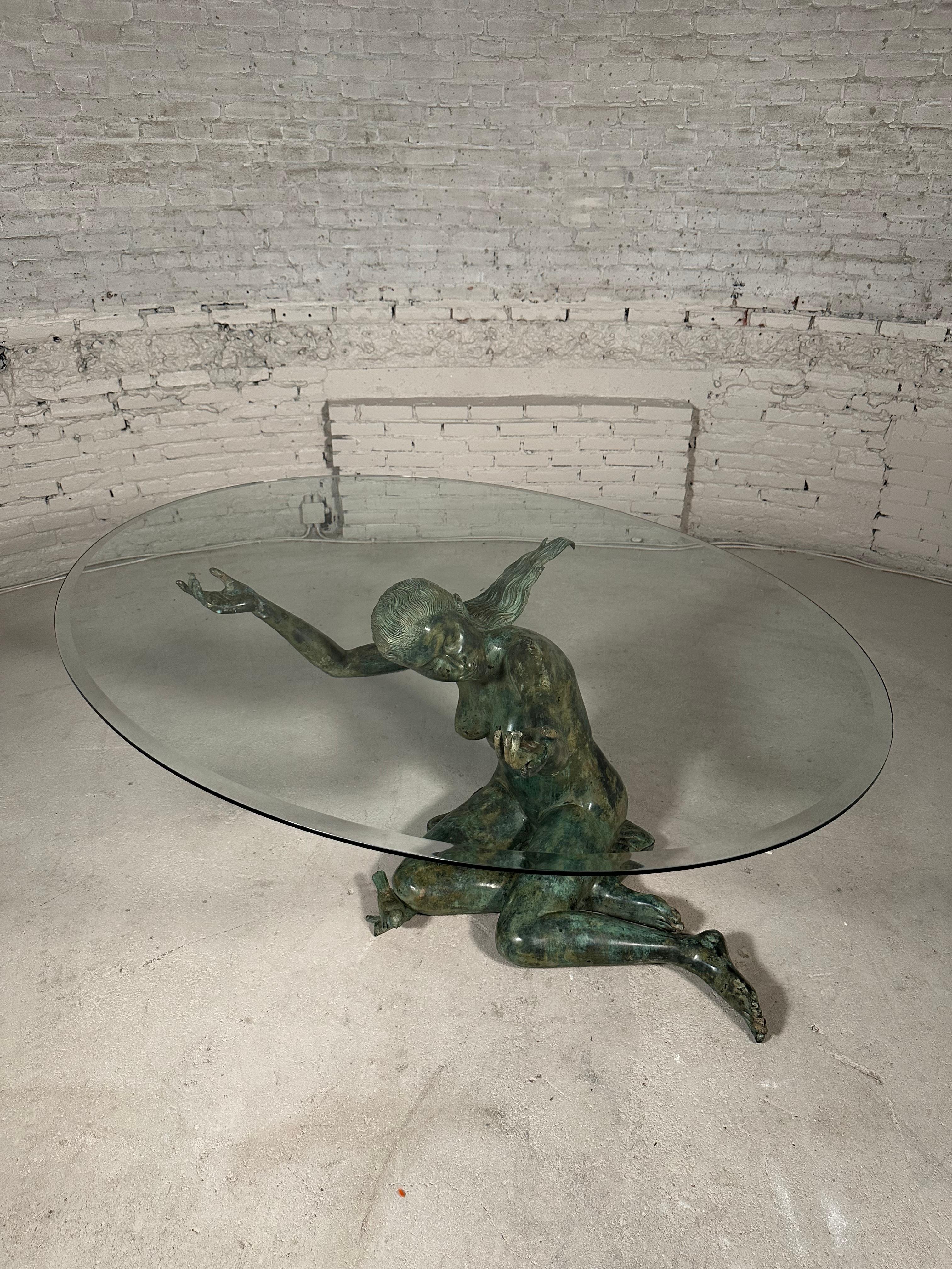 Esta mesa de comedor única presenta una exquisita escultura de bronce de una mujer, acompañada de un pajarito a sus rodillas. Con exquisitos detalles, la escultura sostiene un tablero de cristal. Esta pieza de los años 70 muestra la belleza del arte