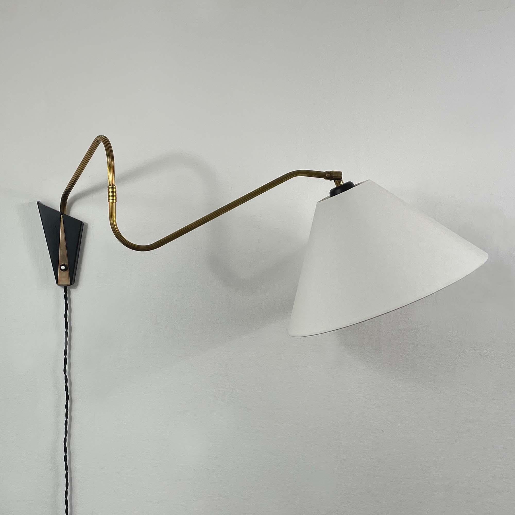 This unusual minimalist mid-century adjustable and articulating vintage wall light was designed and manufactured in Germany by COSACK Leuchten in the 1950s.

The lamp features an off-white fabric lampshade and a naturally aged brass articulating