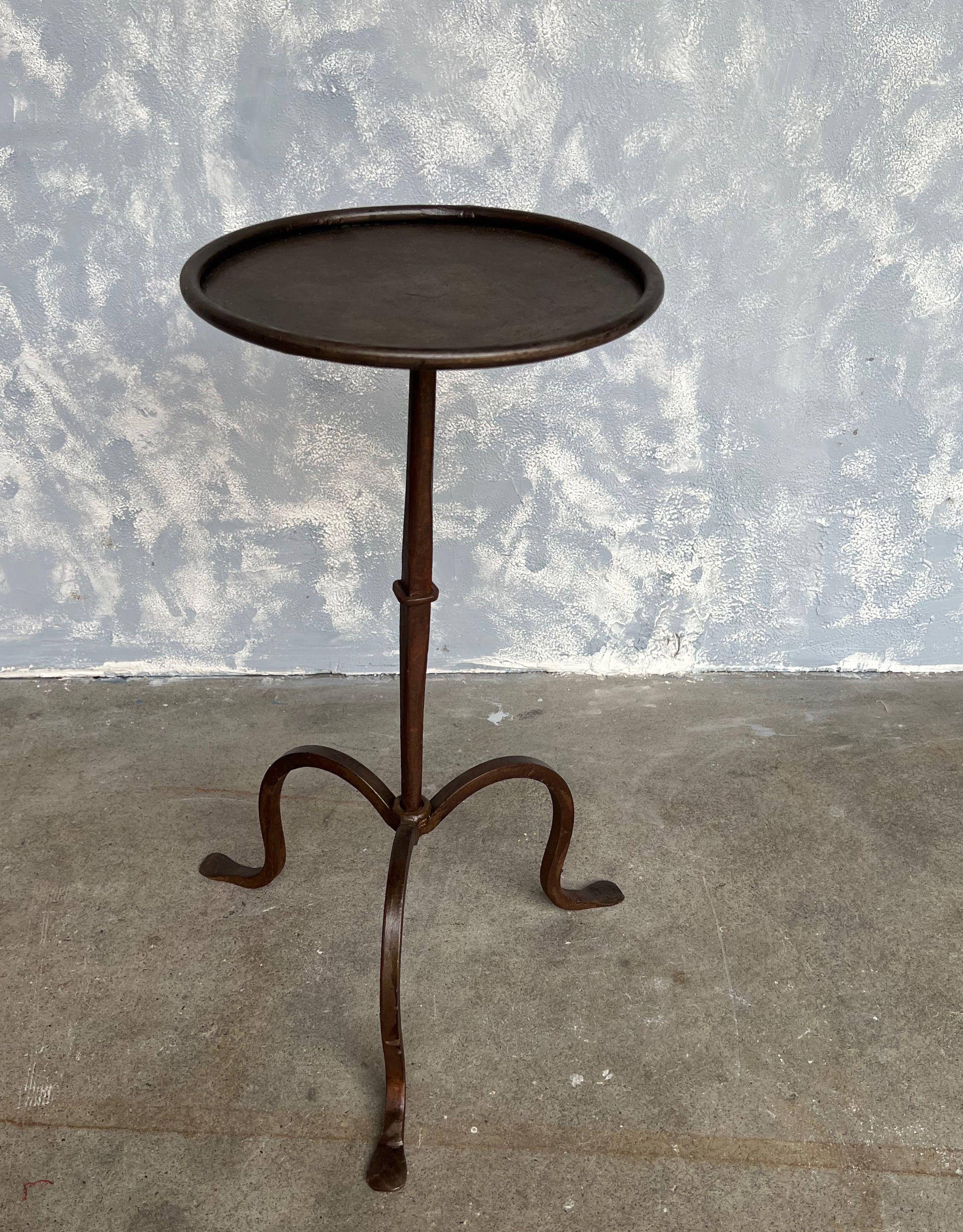 Small iron and metal end table with a tripod base, a central ring detail on the stem, and a ring surround at the top. Perfect for a drink, it can easily be moved around as needed. Beautiful bronzed patina. 

Spanish, 1950s. Very good vintage