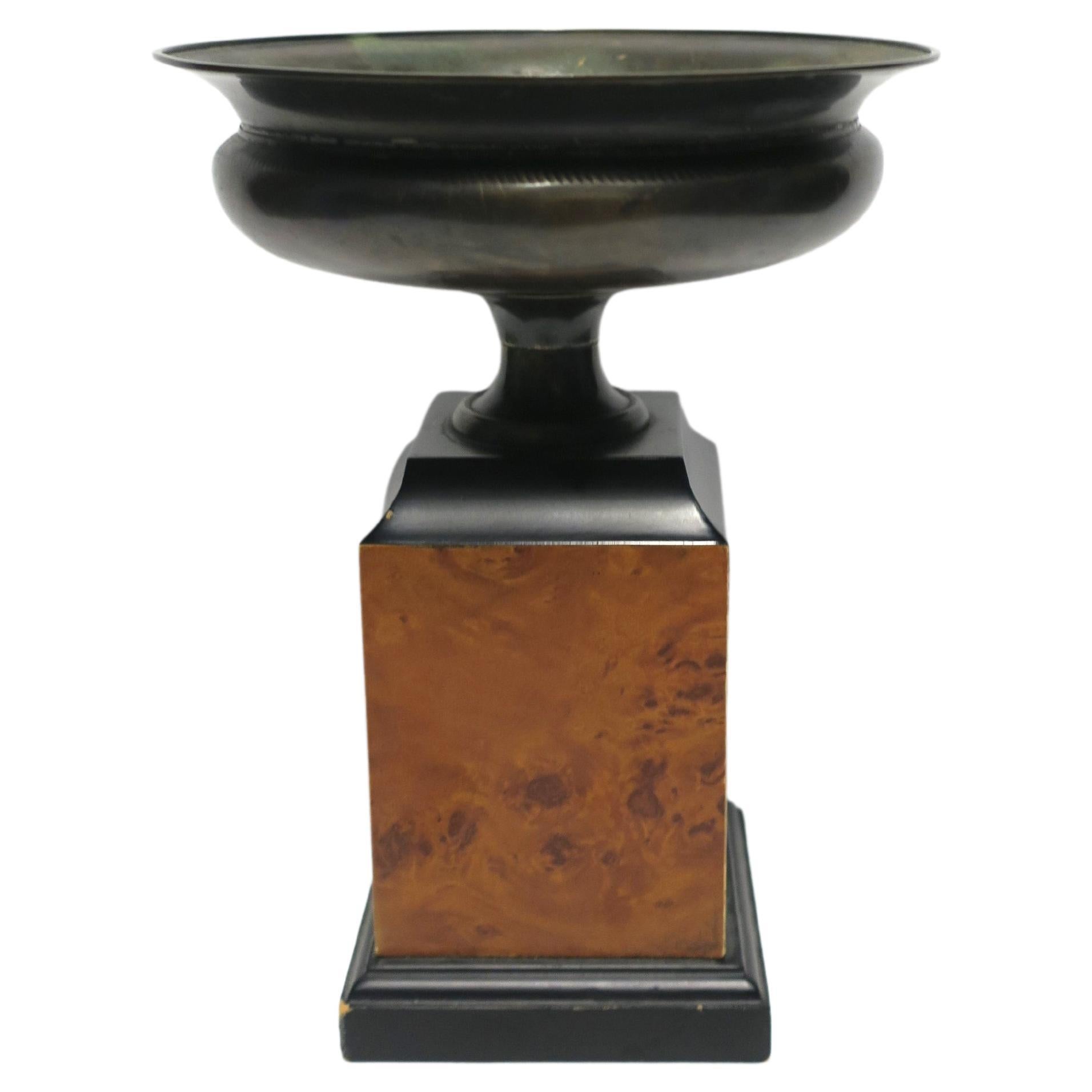 A bronzed metal urn attached to a black wood column plinth base with a brown laminated veneered burl, in the Neoclassical design style, circa 1970s. Great as a standalone piece, or to hold a flower/plant (jardinière), or other items (such as