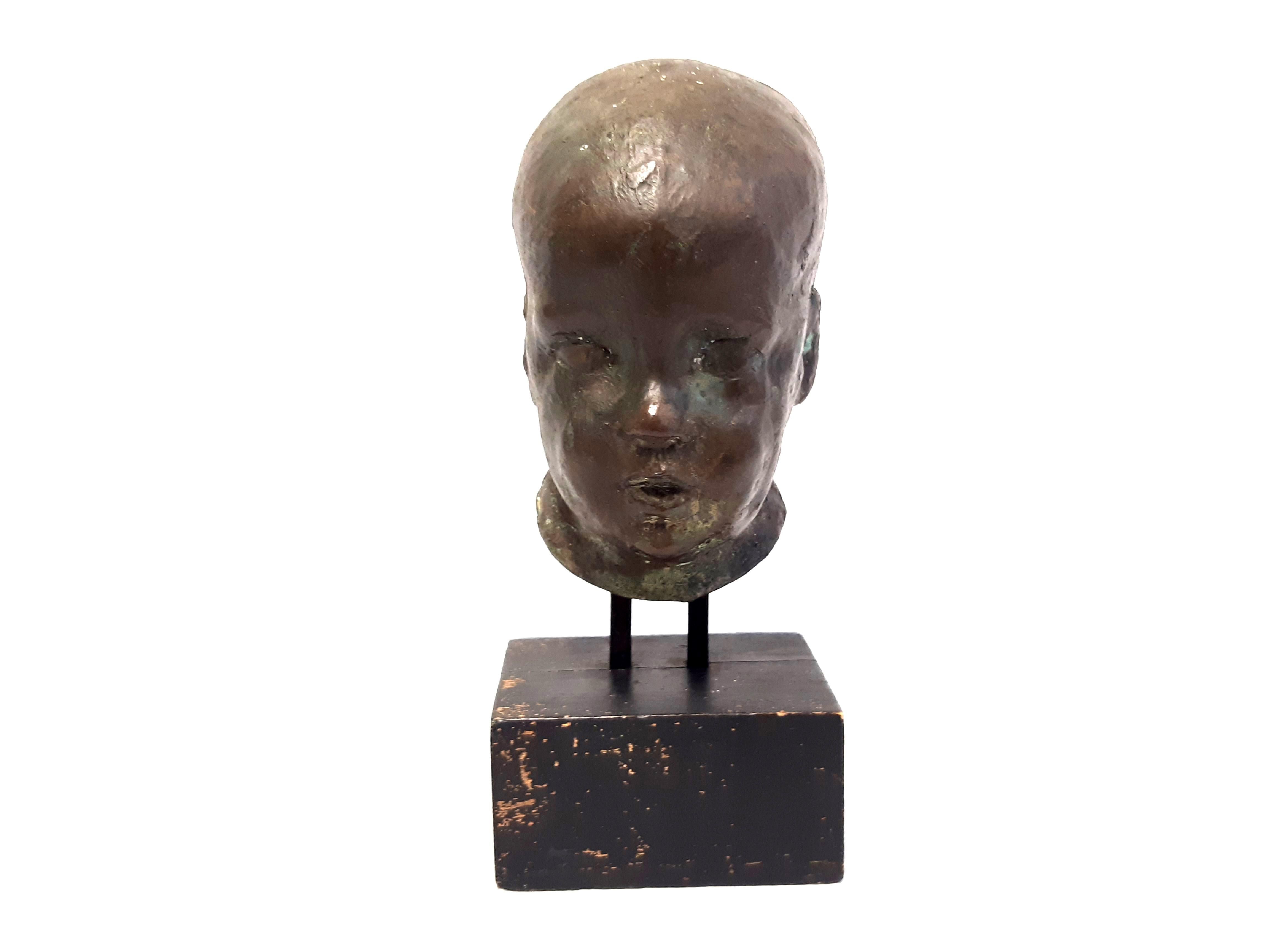 Bronzekopf eines Kleinkindes, auf Holzsockel montiert, wohl Anfang 20. Jhd., mit Kunstharz gefüllt. Nicht signiert.