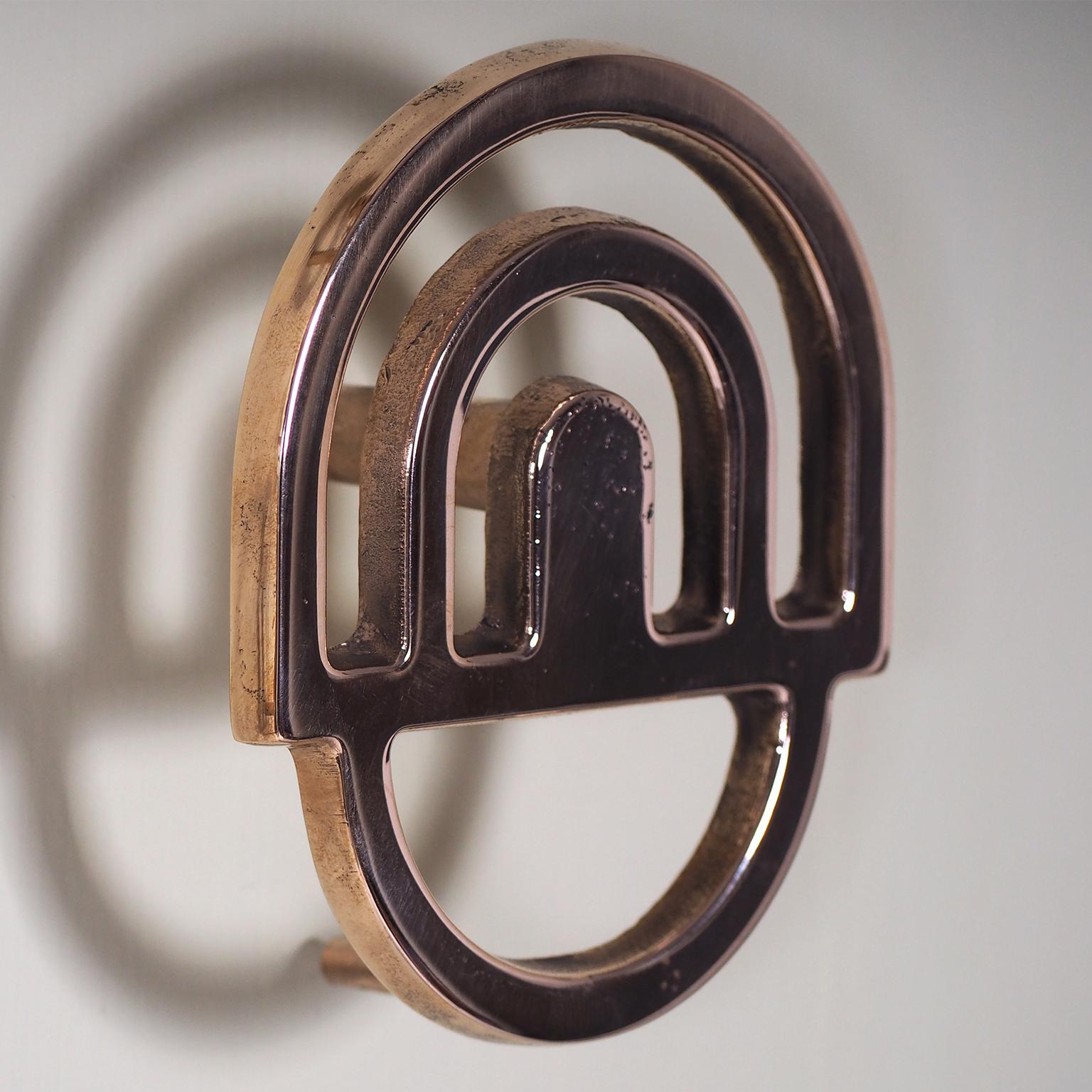 Set of 2 solid bronze hooks
Designed by Alessandro Zambelli 
Made in Italy

Set of two casting bronze wall hooks that reminds to the architecture of the early 1900. A contrast between the severity of geometric structure and imperfection of bronze