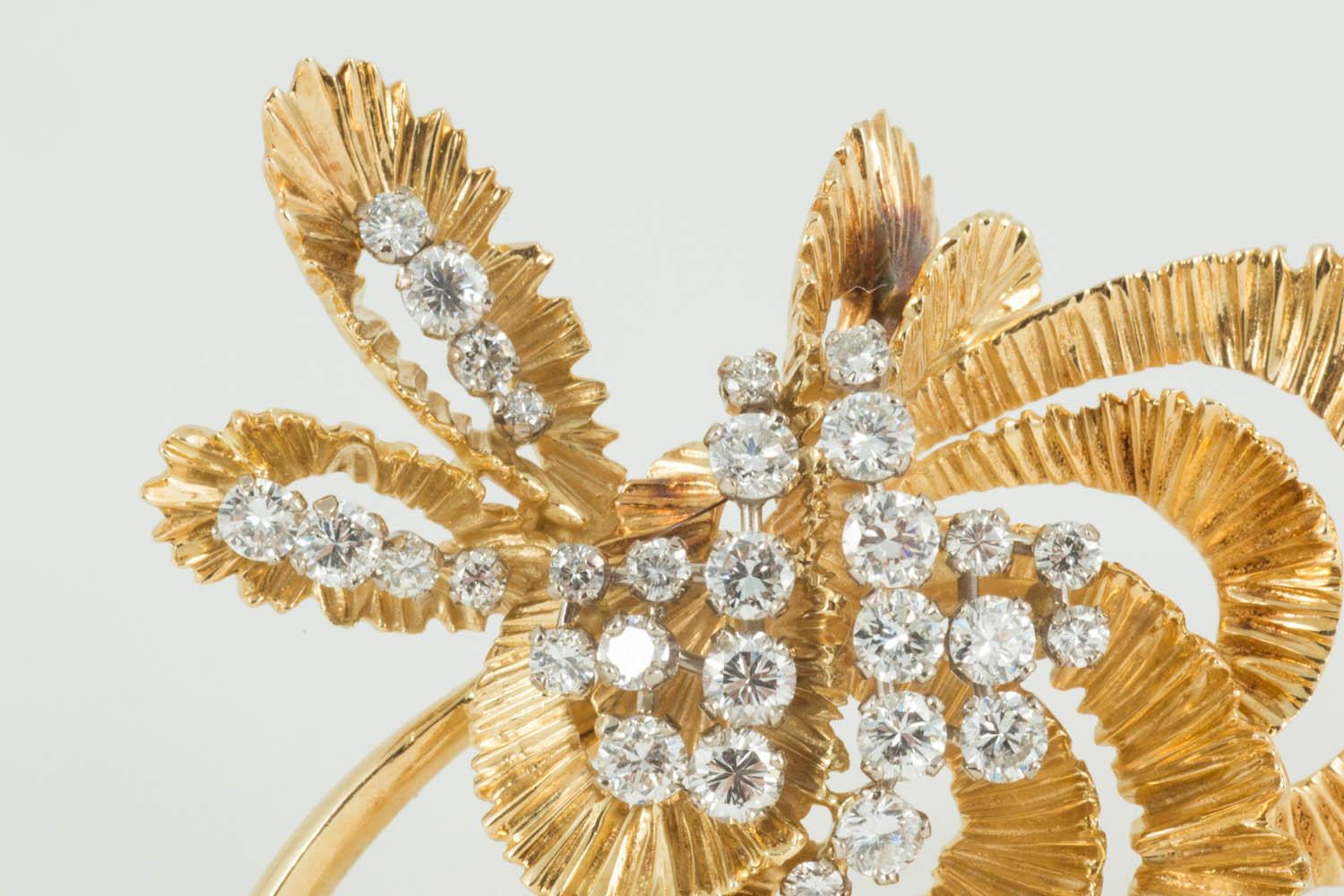 18 carat yellow gold spray brooch by Kutchinsky in the shape of a flower. The gold is of a textured bark design and is set with 30 brilliant cut diamonds of particularly bright quality. Signed Kutchinsky and hallmarked London 1968.
Measures 55mm in