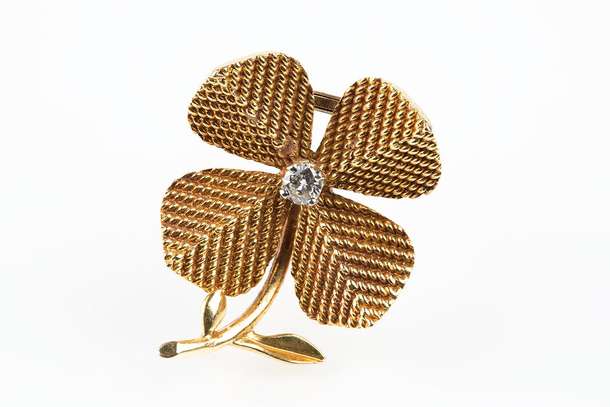 A heavy quality 18 karat yellow gold brooch in the form of a four leaf clover. Beautifully textured design with a single brilliant cut central diamond and a two pronged clip fitting. Signed Sterle Paris with accompanying French marks of the eagles