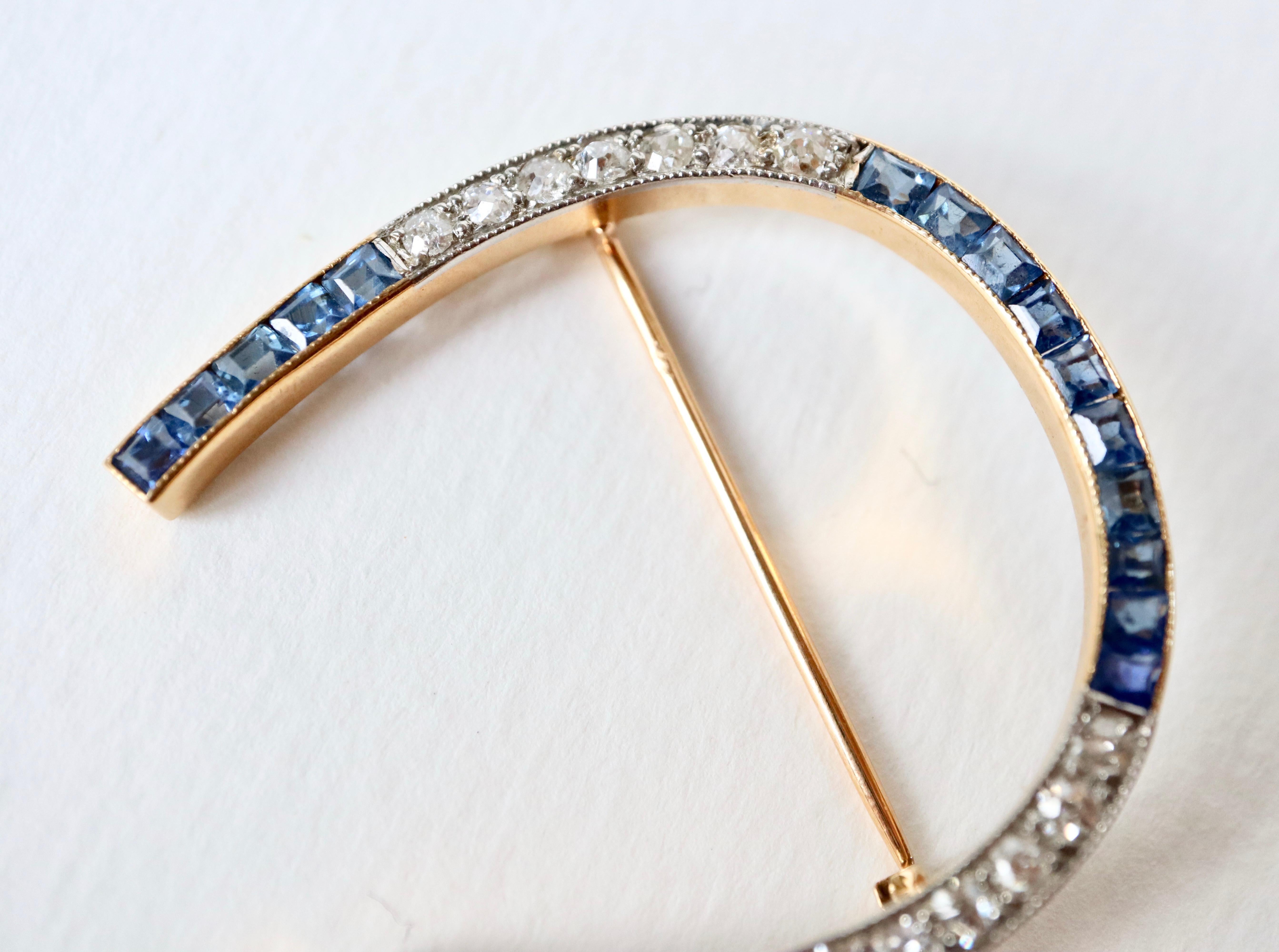 Horseshoe brooch circa 1920 in 18 kt yellow gold adorned with 20 calibrated sapphires and 14 old-cut diamonds for a total weight of approximately 0.7 carats mounted on platinum. 18 Kt gold and platinum hallmarks. 
The Brooch is Numbered
Height 4 cm