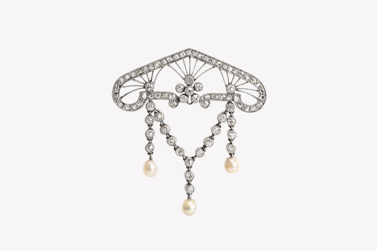 Fan shaped brooch from the Art Nouveau period in platinum and 18 carat yellow gold. The openwork design is set with brilliant and rose cut diamonds with three natural pearl drops. The pearls are hanging from fine diamond chains giving movement to