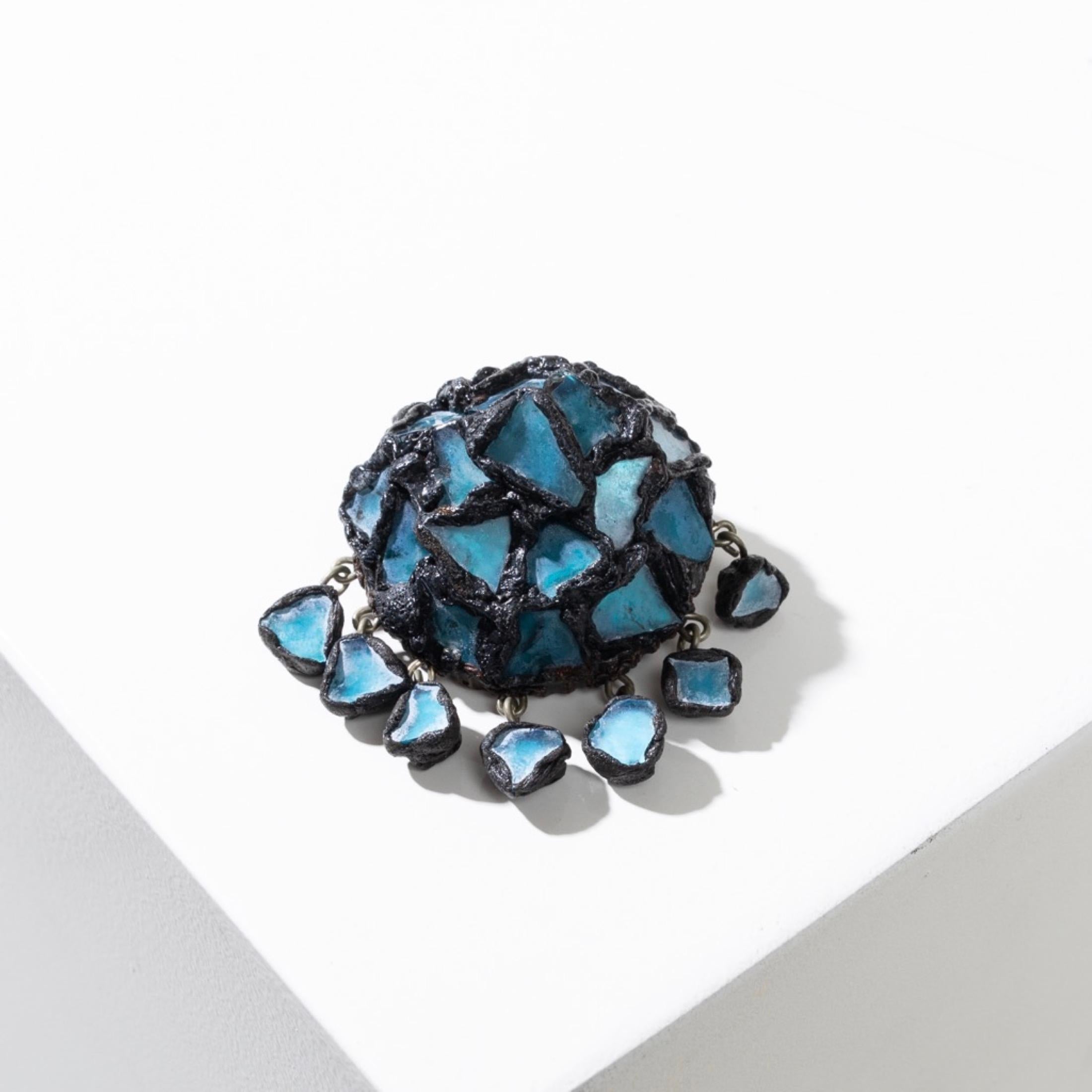 This black Talosel brooch by Line Vautrin, adorned with small blue mirrors artistically interlocking in the Talosel, presents a combination of textures and colors that perfectly reflects the work of Line Vautrin.
Seven small blue mirrors hanging