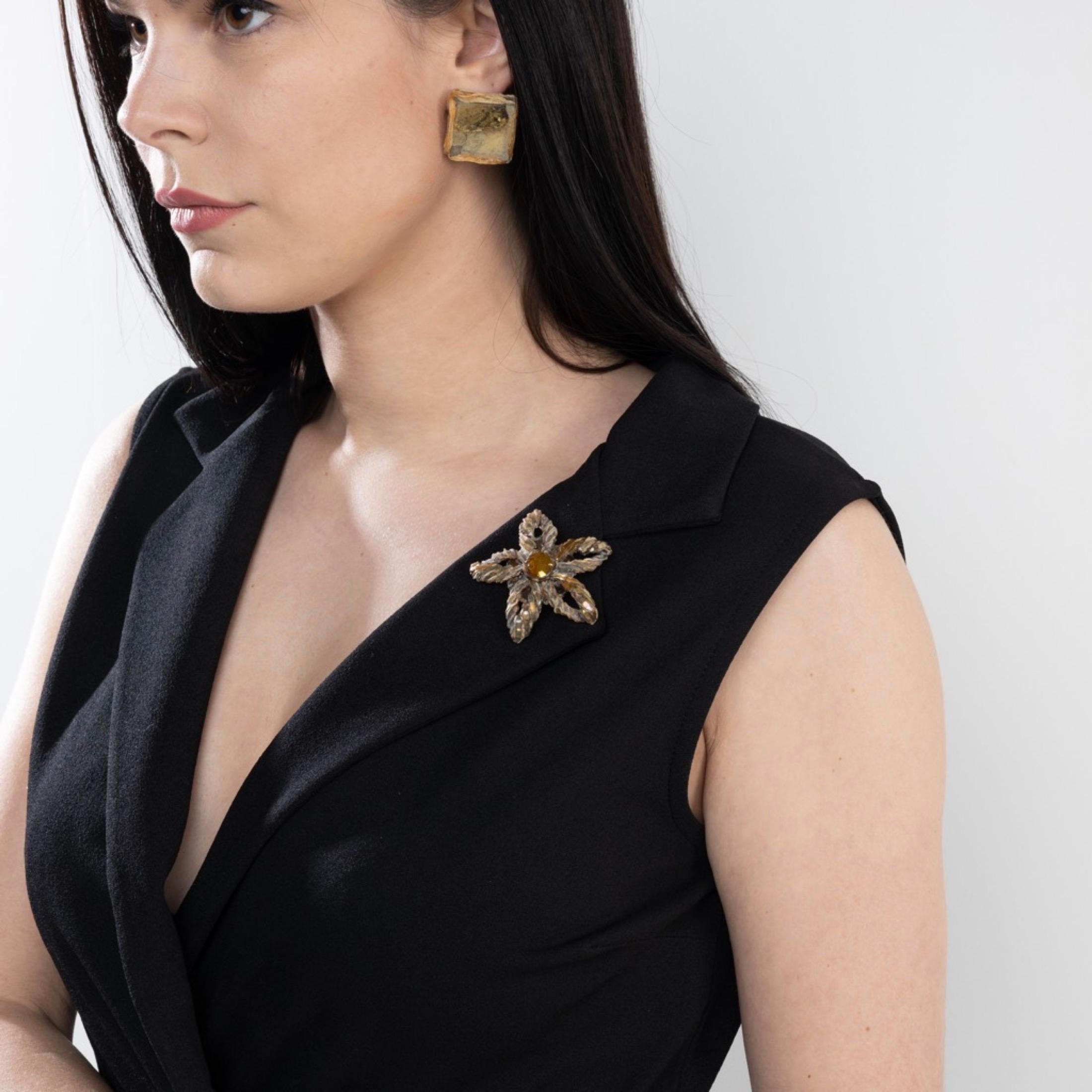 This light brown Talosel brooch by Line Vautrin is a unique and elegant piece, adorned with golden star-shaped mirrors and a small convex round mirror in the center. The points of the star are formed by Talosel which has been carefully scarified by