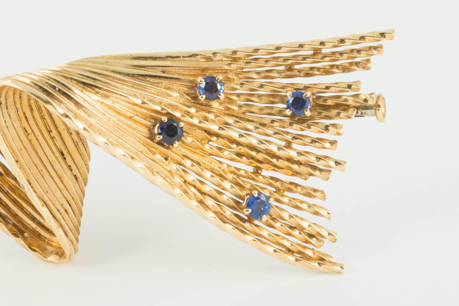 A vintage heavy quality 18 karat yellow gold brooch of abstract design and set with 5 sapphire collets. This  well made piece uses textured wirework lines linked together to give a twisted wave like appearance. French marks on the pin and signed