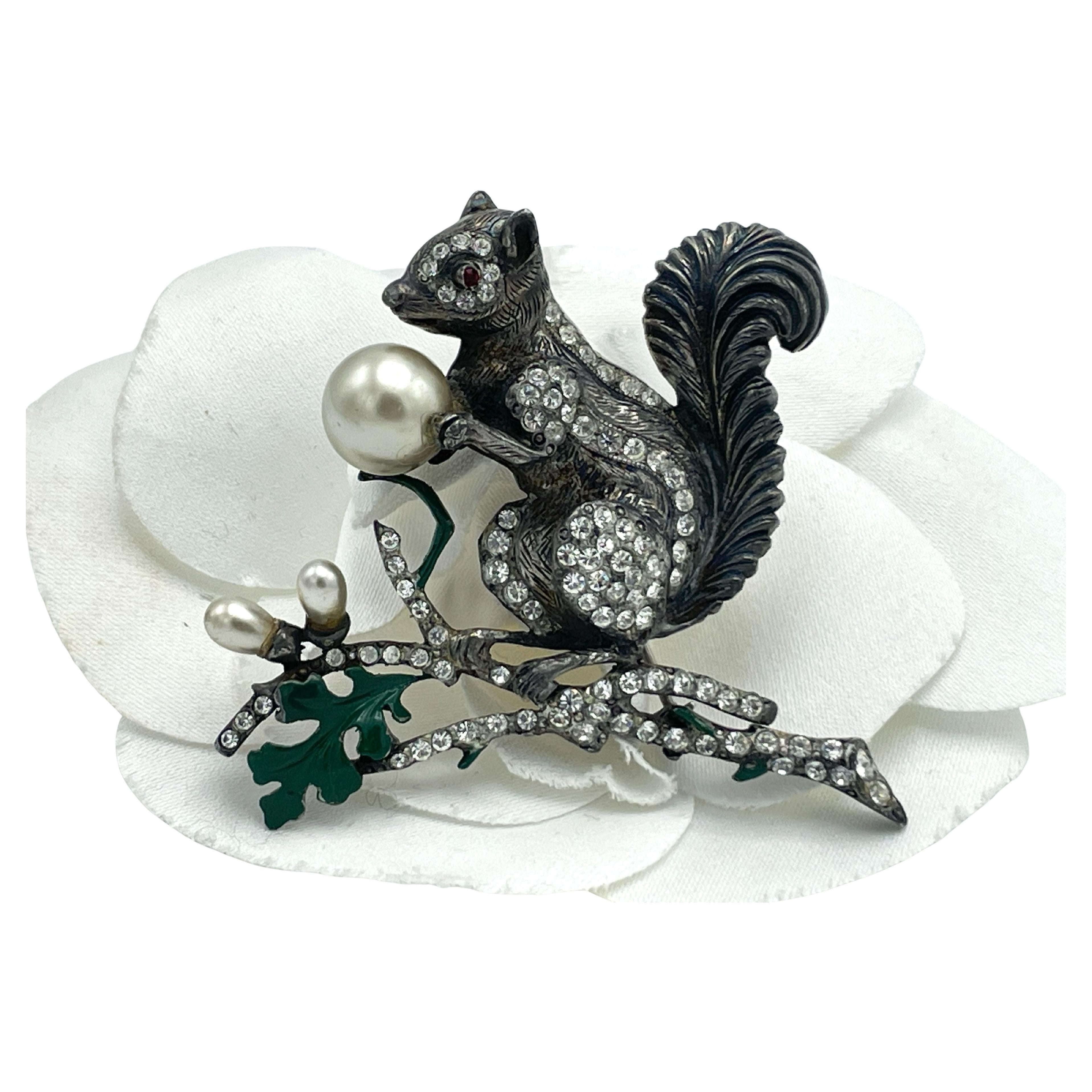 Brooch in the shape of a squirrel, signed STARET USA, which is partially set with small rhinestones. It holds a large pearl, which is probably meant to represent a nut! Sitting on a rhinestone-studded branch with a green acorn leaf, signed STARET