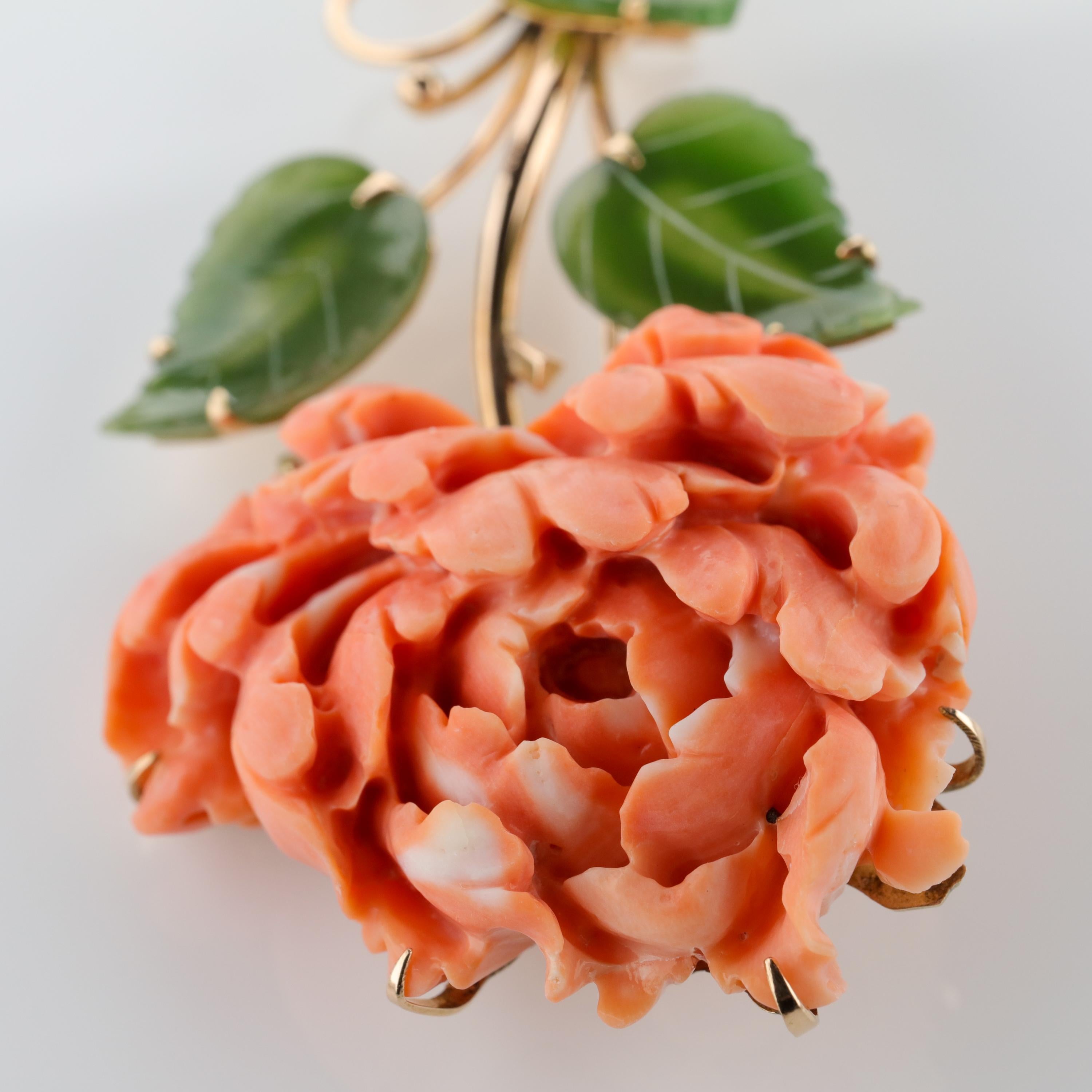 This spectacular and unique brooch features a hand-carved coral chrysanthemum blossom executed with such skill and artistry that if you lay the brooch on a table, look away from it, then look back at it, it will completely fook your eye. It looks