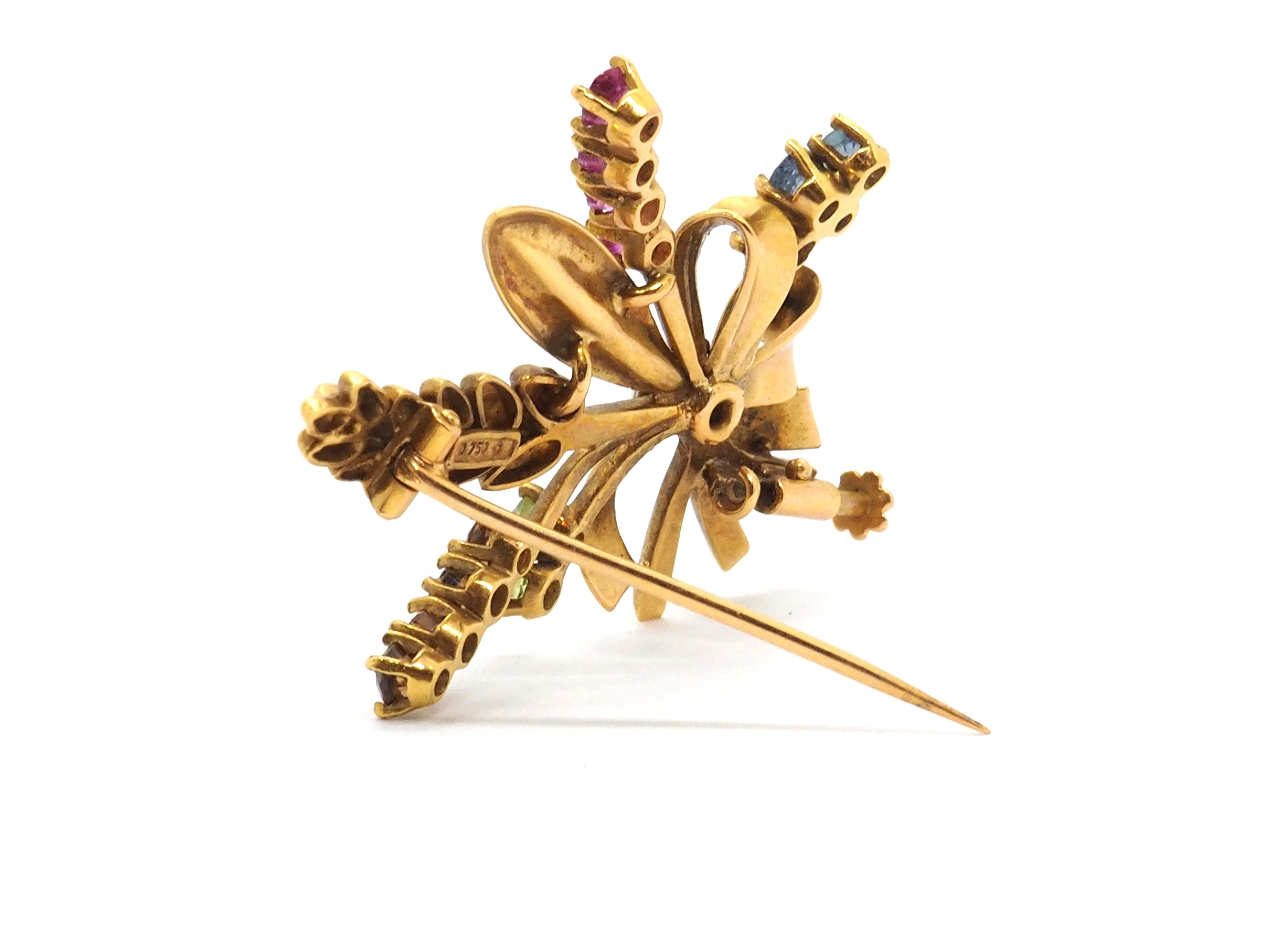 Brooch shaped like a bouquet of flowers and spikes with a tie, crafted in 18 karats yellow gold. The brooch has also the option to be used as pendent.

Each of the flowers is decorated with different gemstones, one with 4 blue topaz, another one has