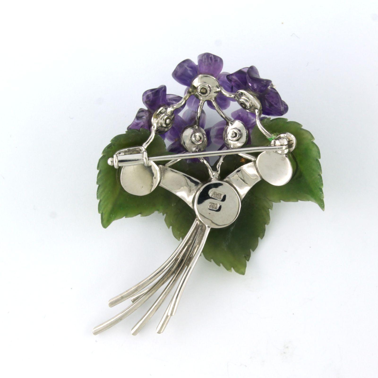 18k white gold brooch in the shape of a bunch of flowers, set with amethyst flowers, jade leaves and single cut diamonds, total 0.05ct - F/G - VS/SI

detailed description:

The size of the brooch is 6.1 cm x 4.5 cm wide

weight: 21.2 grams

set