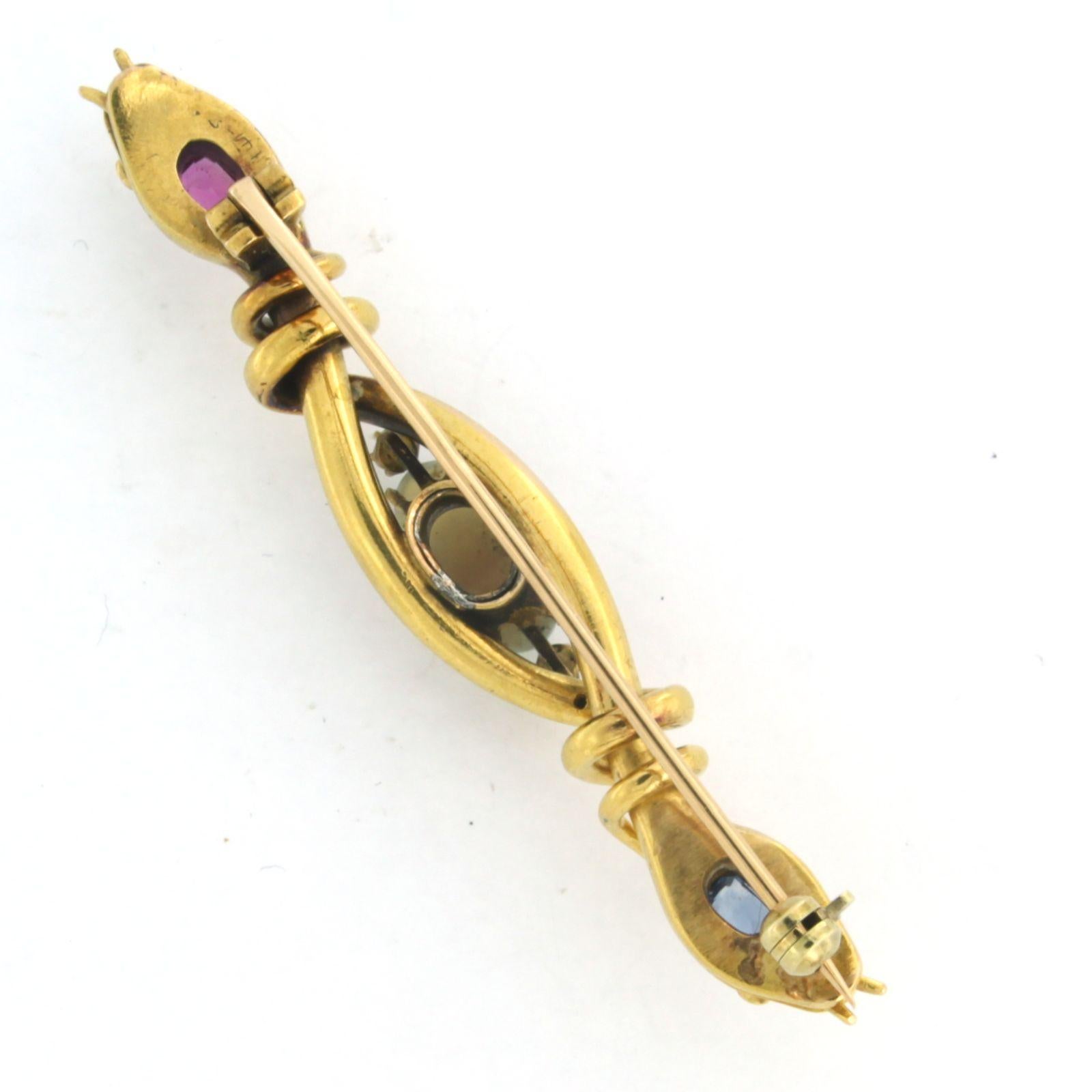 18k yellow gold brooch in the shape of 2 snake heads with opal, sapphire, ruby ​​and rose cut diamond. 0.06ct. - G/H - SI

detailed description:

dimensions of the brooch are 6.0 cm wide by 1.0 cm high

weight 9.8 grams

occupied with

- 1 x 1.1 cm