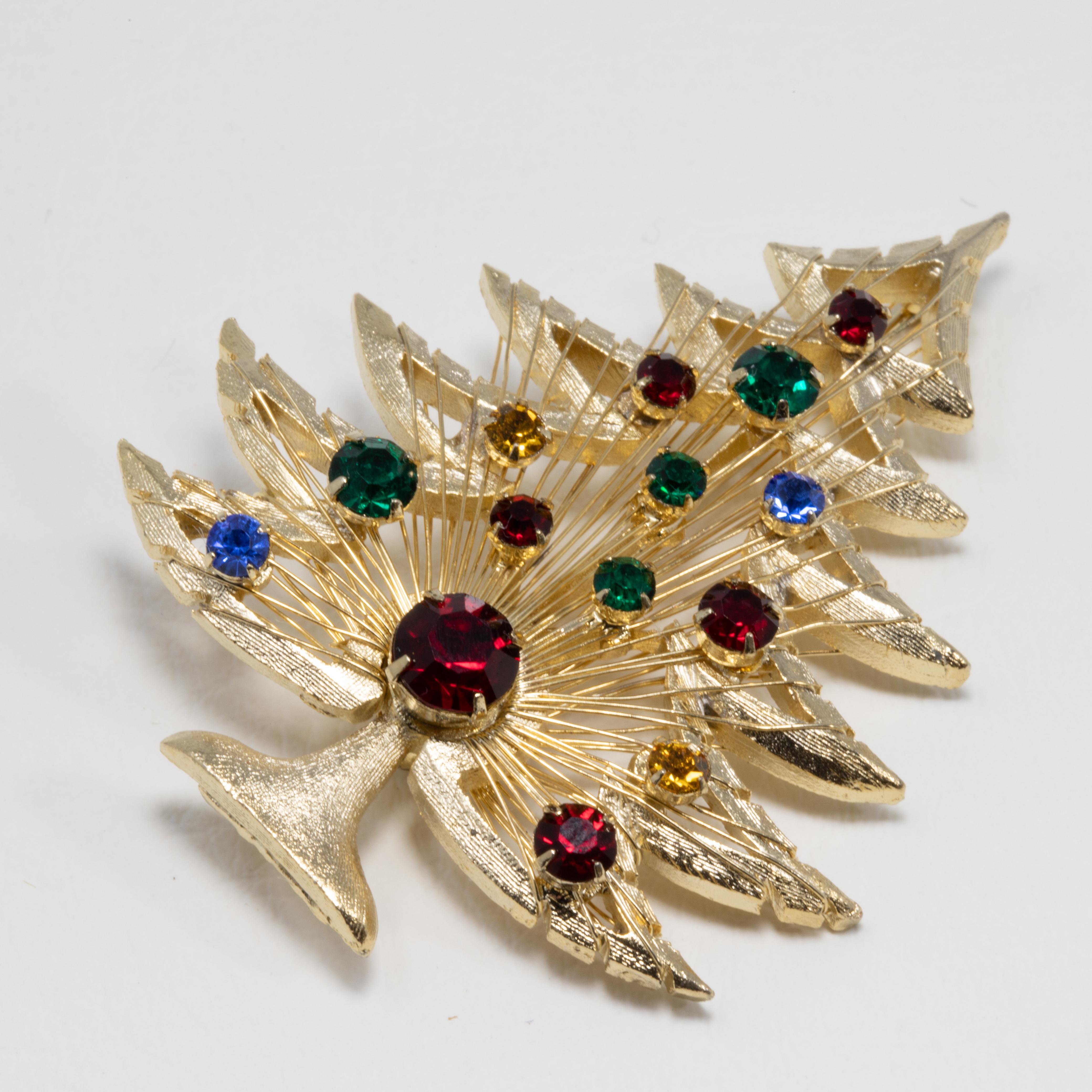 A vintage Christmas tree brooch in gold finish. The perfect festive accessory!  The wired tree is accented with red, green, blue, and orange crystals, all in prong settings.

Hallmarks: © Brooks