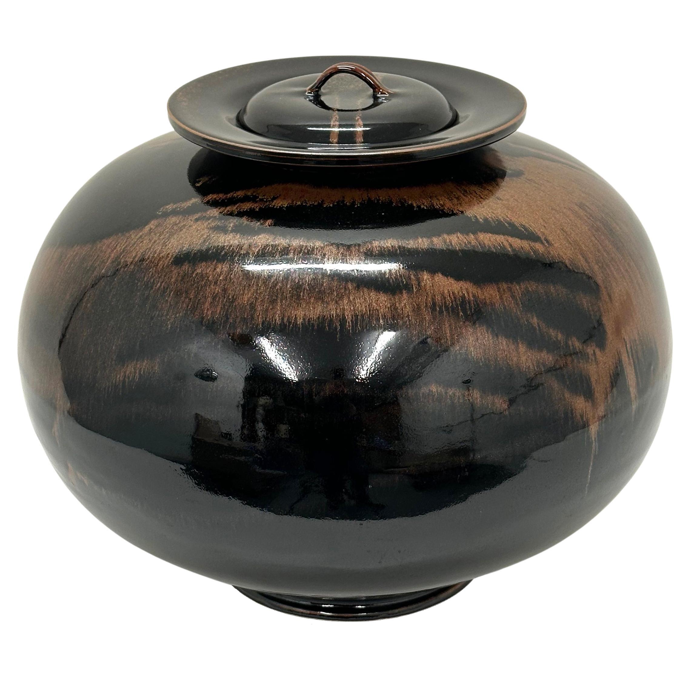 A large globular vase with cover in honan tenmoku glaze by Brother Thomas Bezanson. USA, 1993. Signed. Pucker Gallery catalog number, TH975. Rotating display base included (not shown).

Brother Thomas Bezanson was an internationally renowned ceramic
