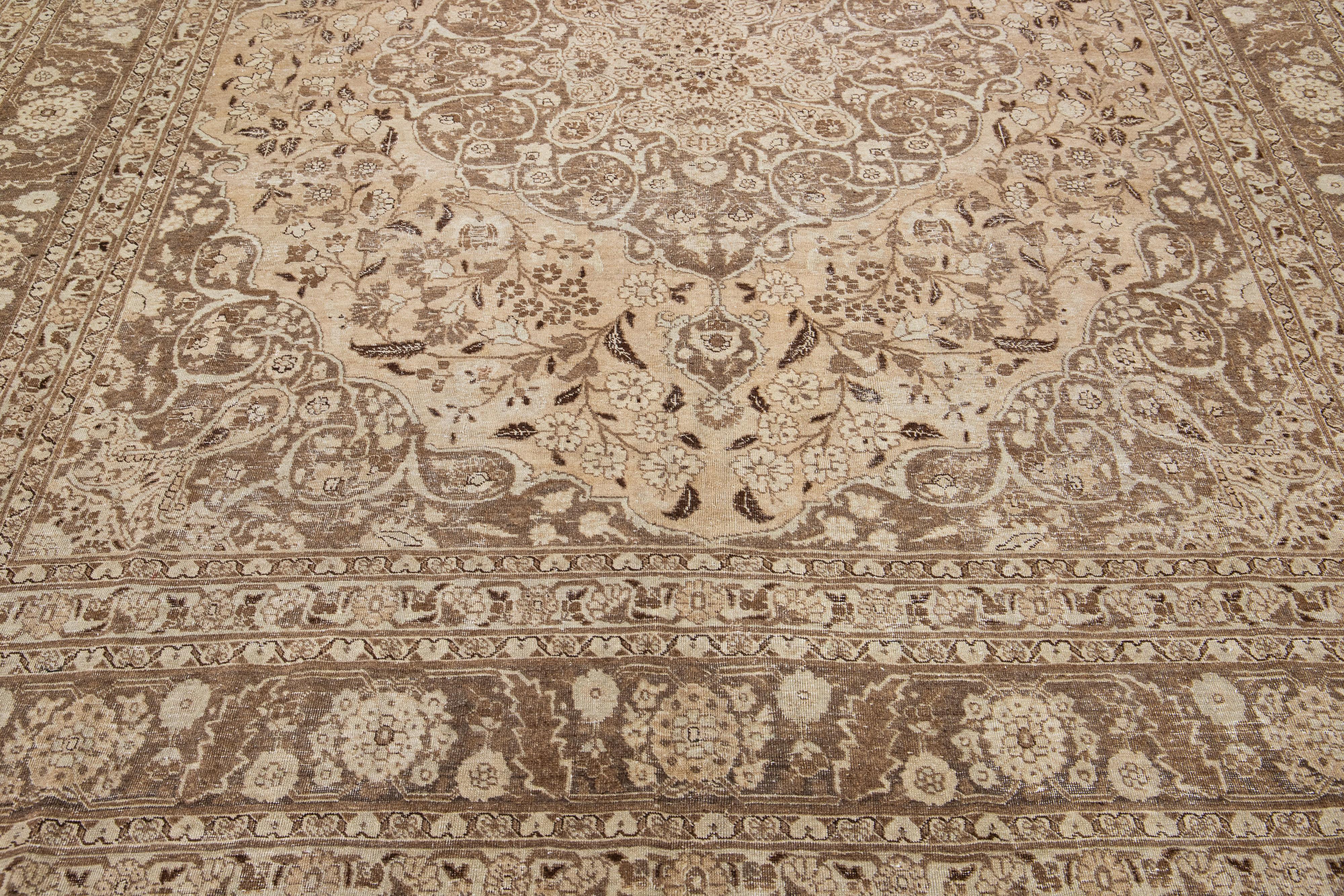 Beautiful antique Persian hand-knotted wool rug with a beige color field. This piece has a brown-designed frame and accents in a gorgeous all-over medallion floral design. Handspun using traditional methods, this rug provides a sophisticated,