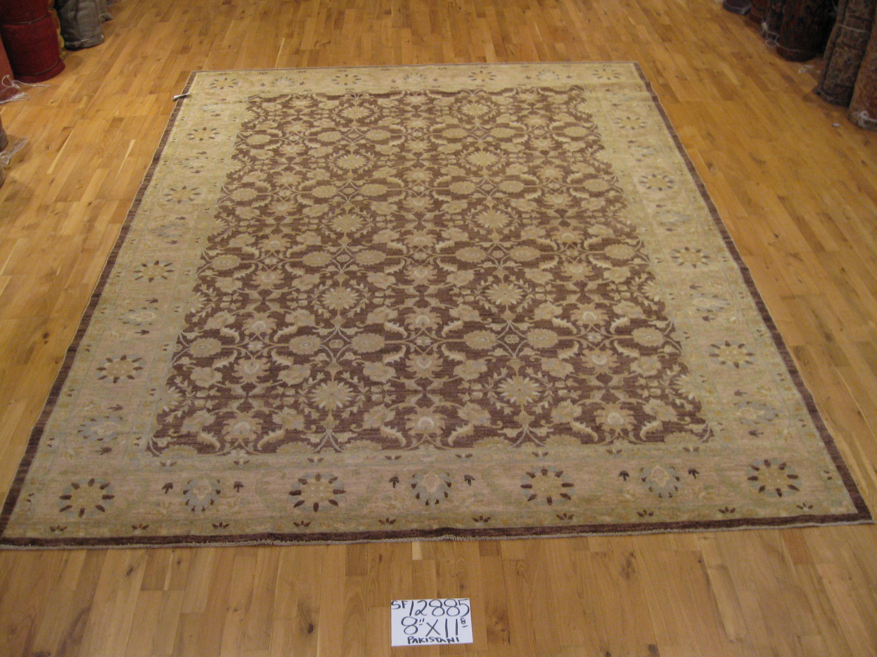 Fine traditional style rug made with vegetal dye. Large brown center panel with wide beige border frame. Floral motif with shades of light blue, pink and yellow/gold. All wool. Hand knotted in Pakistan.