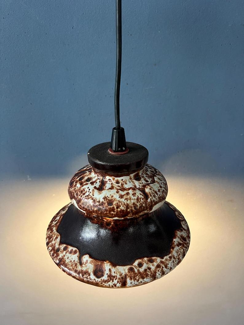 Brown west germany ceramic fat lava pendant lamp. The light spreads a nice warm glow through the holes in the ceramic shape. The lamp requires one E27/26 (standard) lightbulb.

Additional information:
Materials: Ceramic
Period: 1970s
Dimensions: ø