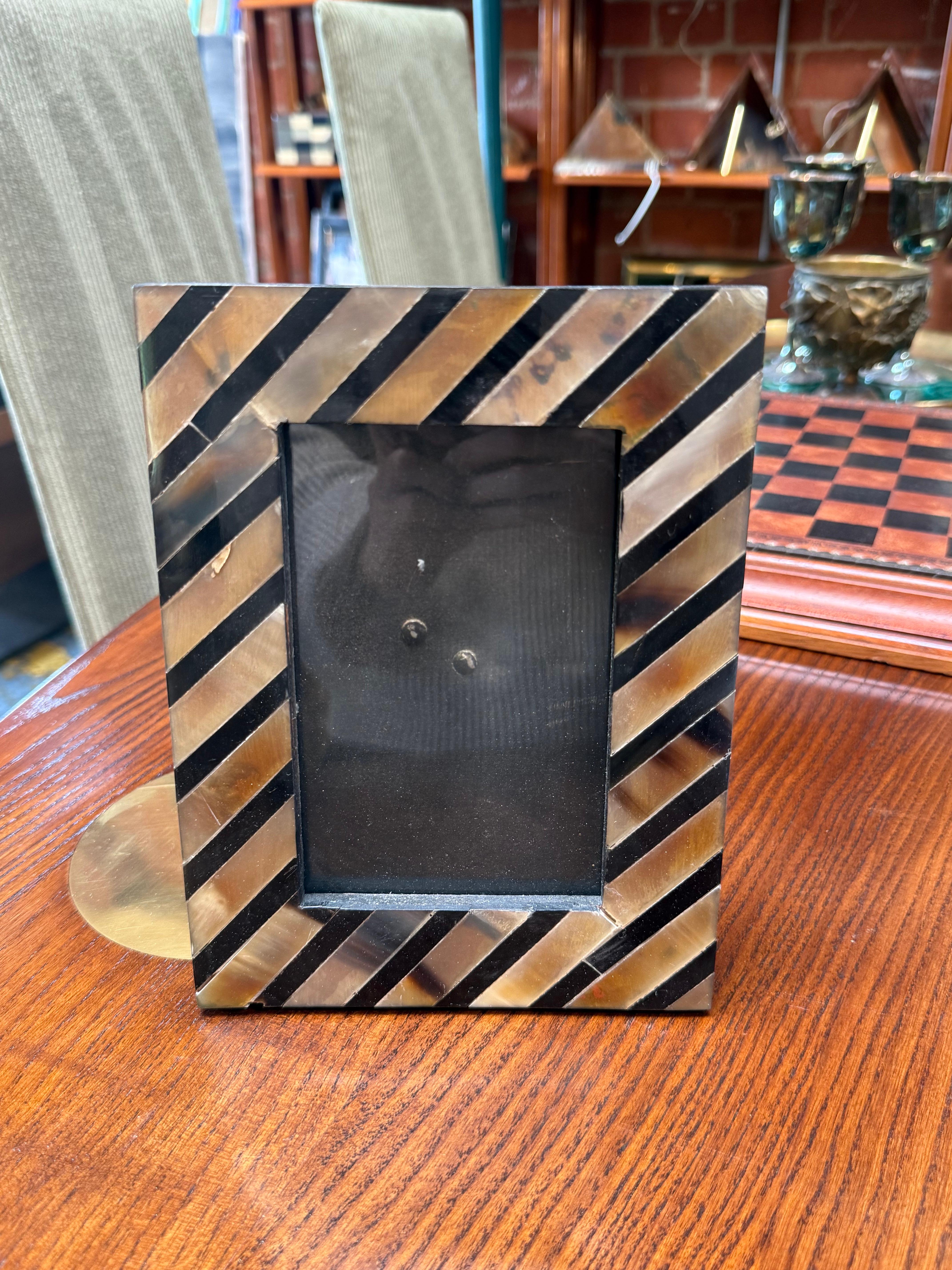 This brown and black chevron striped photo frame exudes warmth and sophistication with its handcrafted, horn-inspired design. The diagonal pattern alternates between glossy brown and deep black inlays, creating a striking geometric look. The frame’s