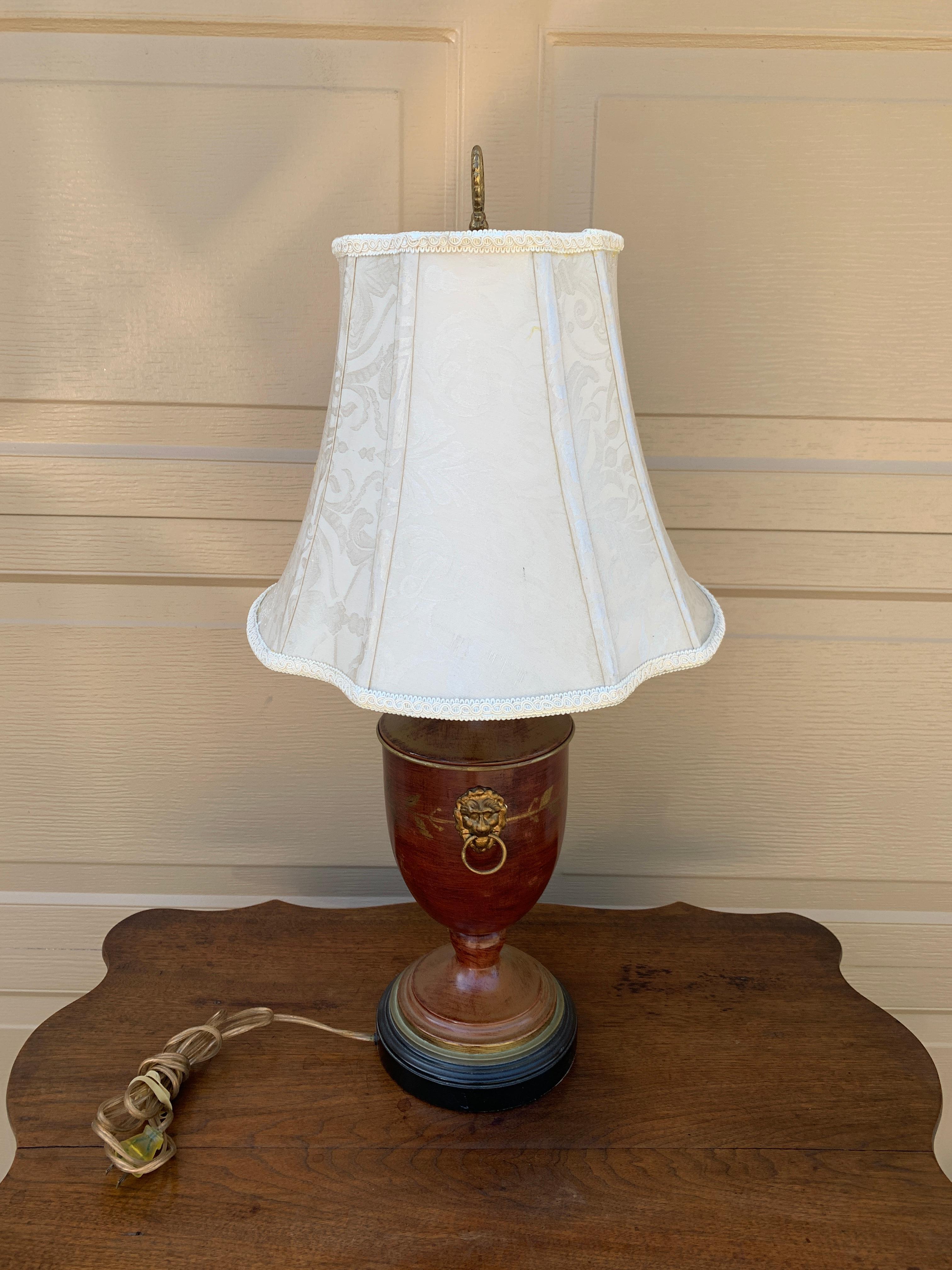 Magnifique lampe vintage de style néoclassique, de couleur marron, avec des accents de feuillage peints en or. Deux têtes de lion en laiton se trouvent de part et d'autre de l'urne. 

États-Unis, fin du 20e siècle

Mesures : 6,5 