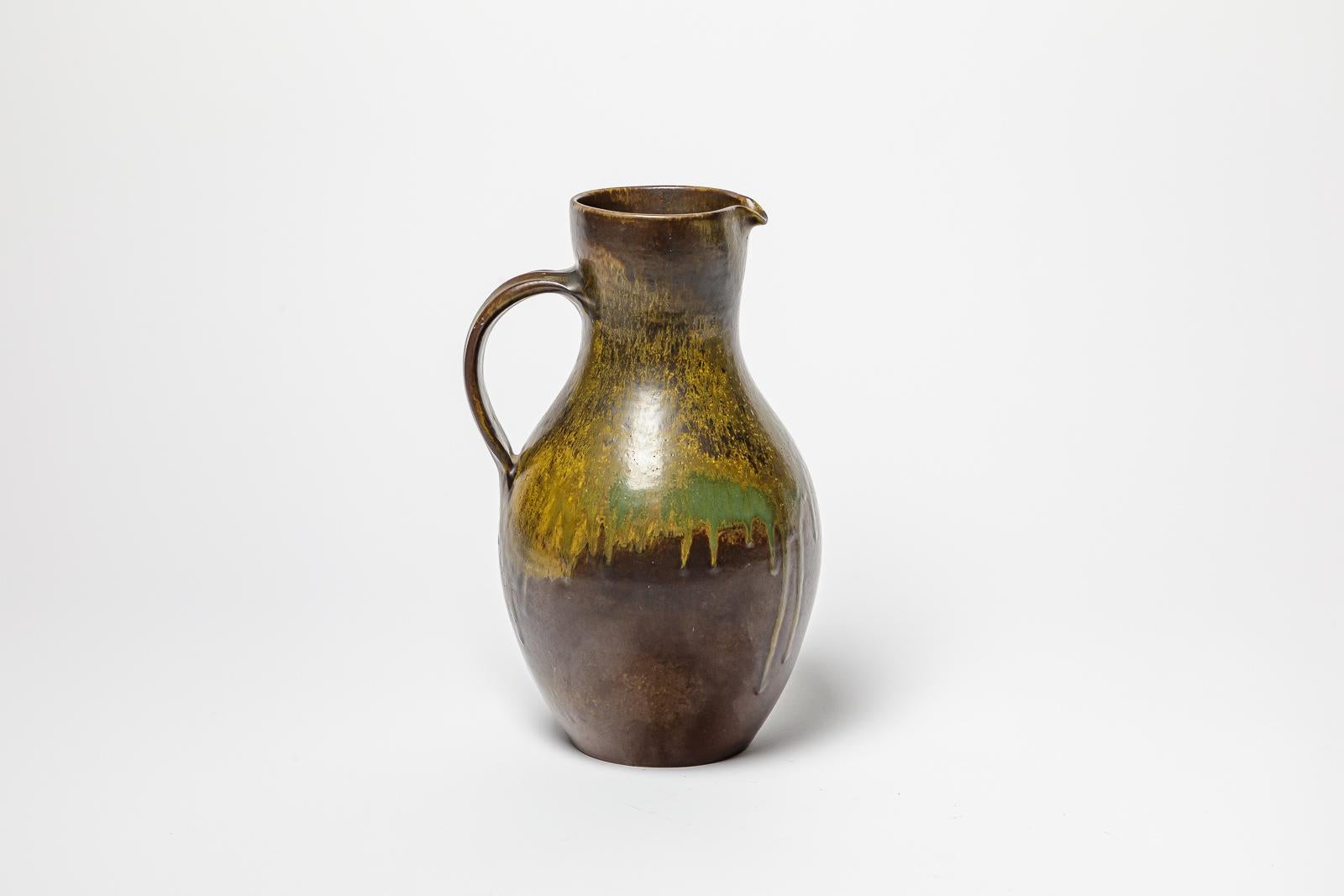 Brown and green glazed ceramic pitcher by Roger Jacques. 
Artist signature under the base. Circa 1960-1970.
H : 11.02’ x 5.9’ x 5.9’ inches.